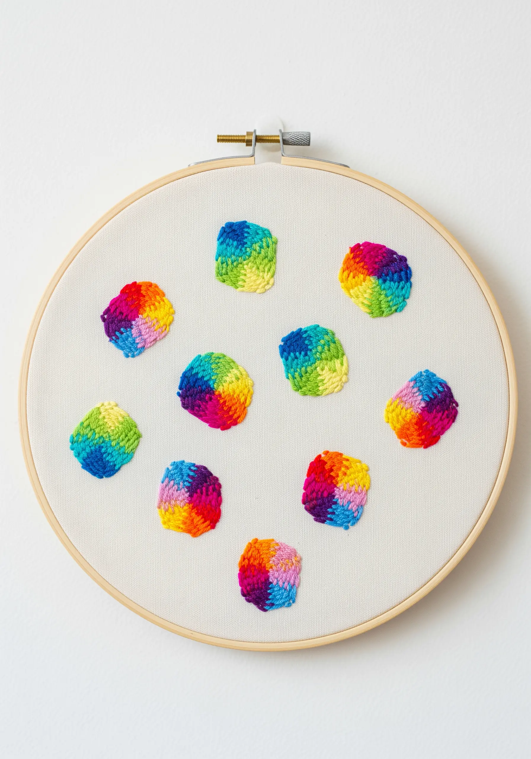 Small, woven-style embroidered squares with vibrant rainbow color gradients.