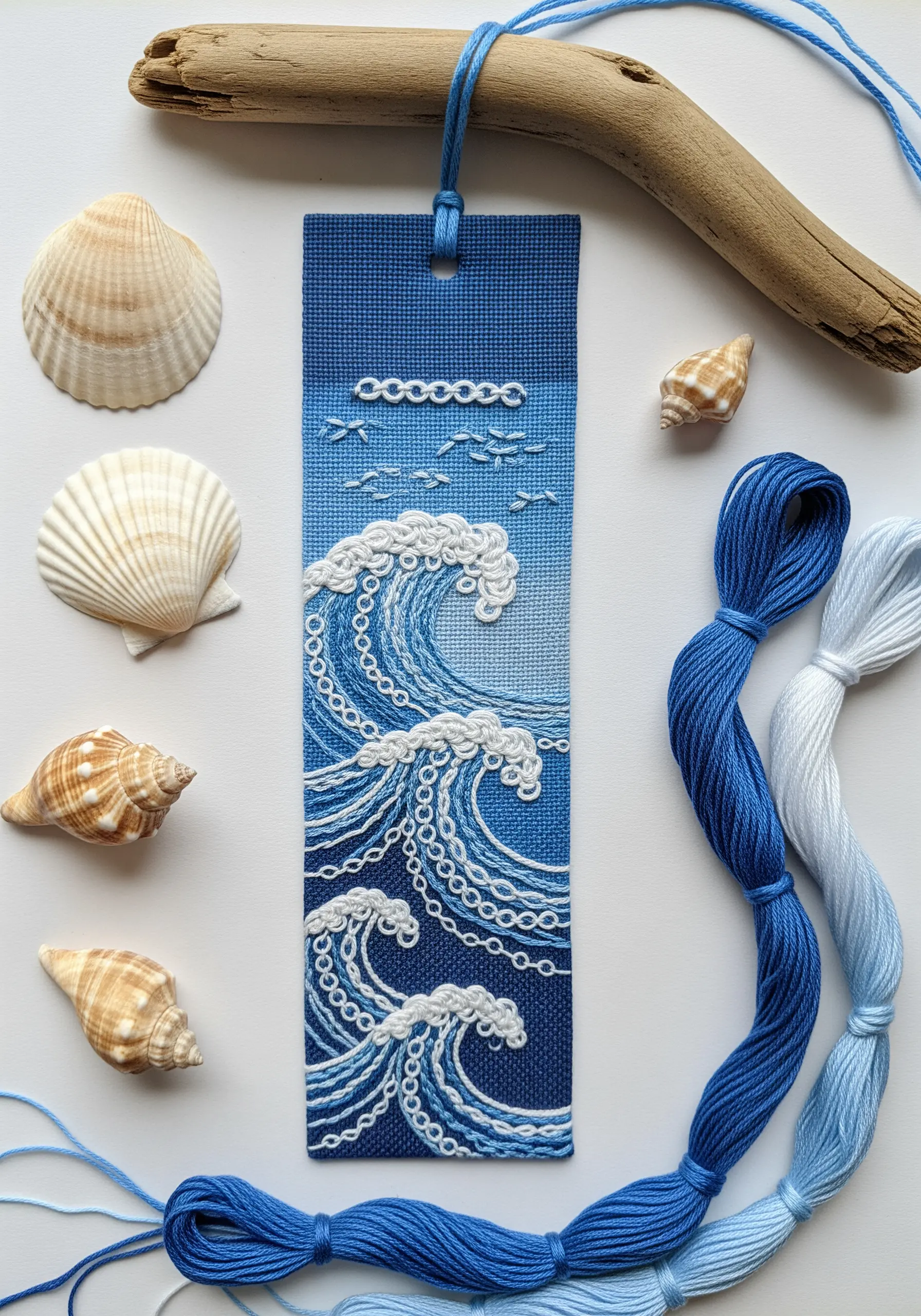 Embroidered ocean wave scene on a blue bookmark, using French knots and chain stitches.