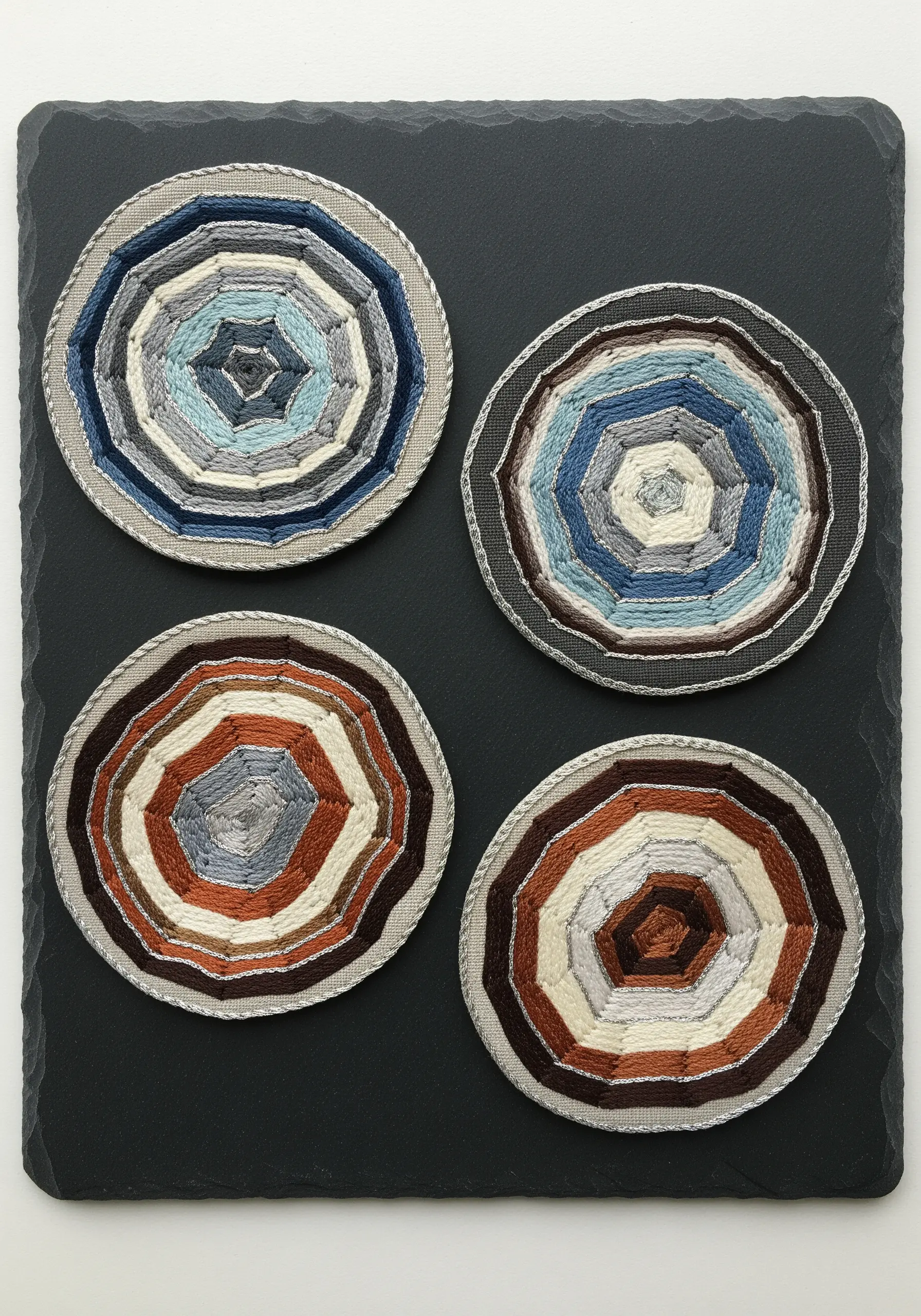 Four round coasters with abstract, concentric wrapped-thread patterns in earth tones.