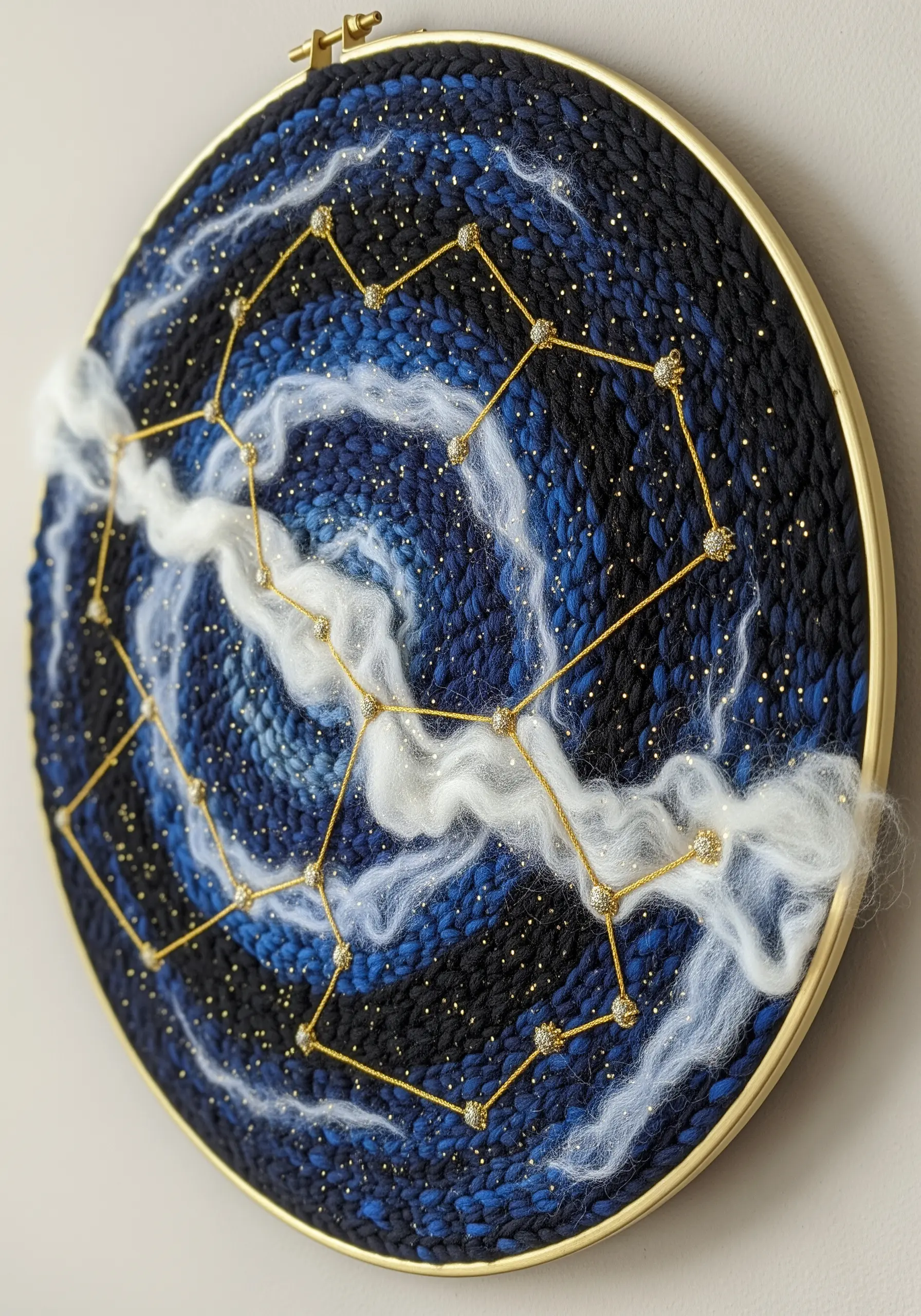A woven hoop with a starry night sky, complete with metallic thread constellations and fiber clouds.