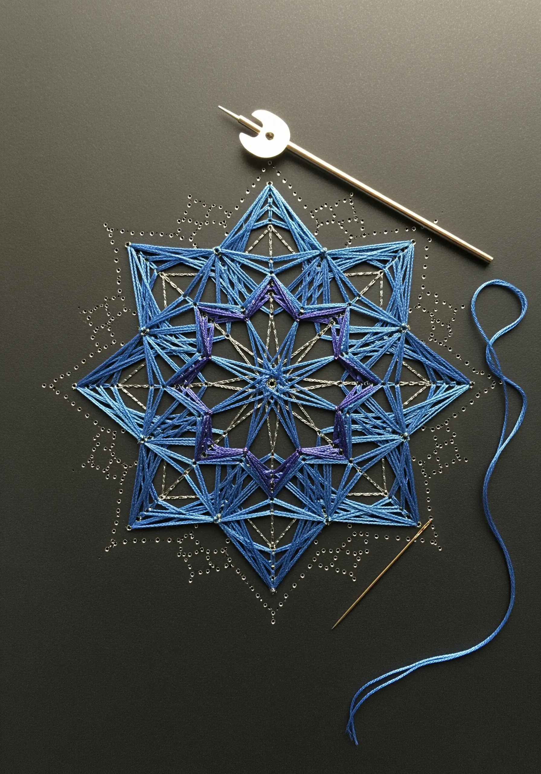 A complex blue string art mandala created by wrapping thread around pins on a dark surface.