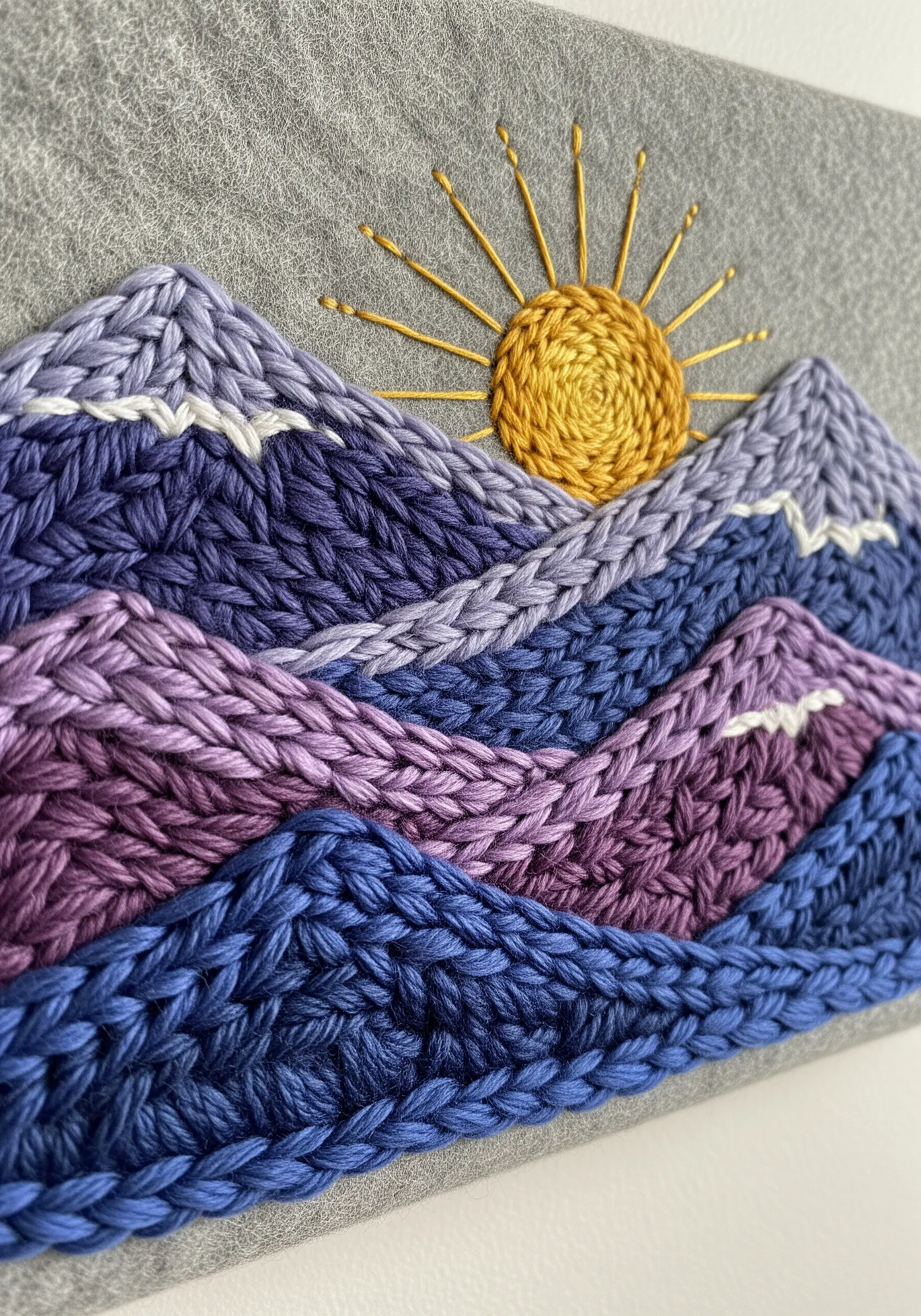 Textured mountain landscape embroidered with thick, braided stitches in shades of purple.