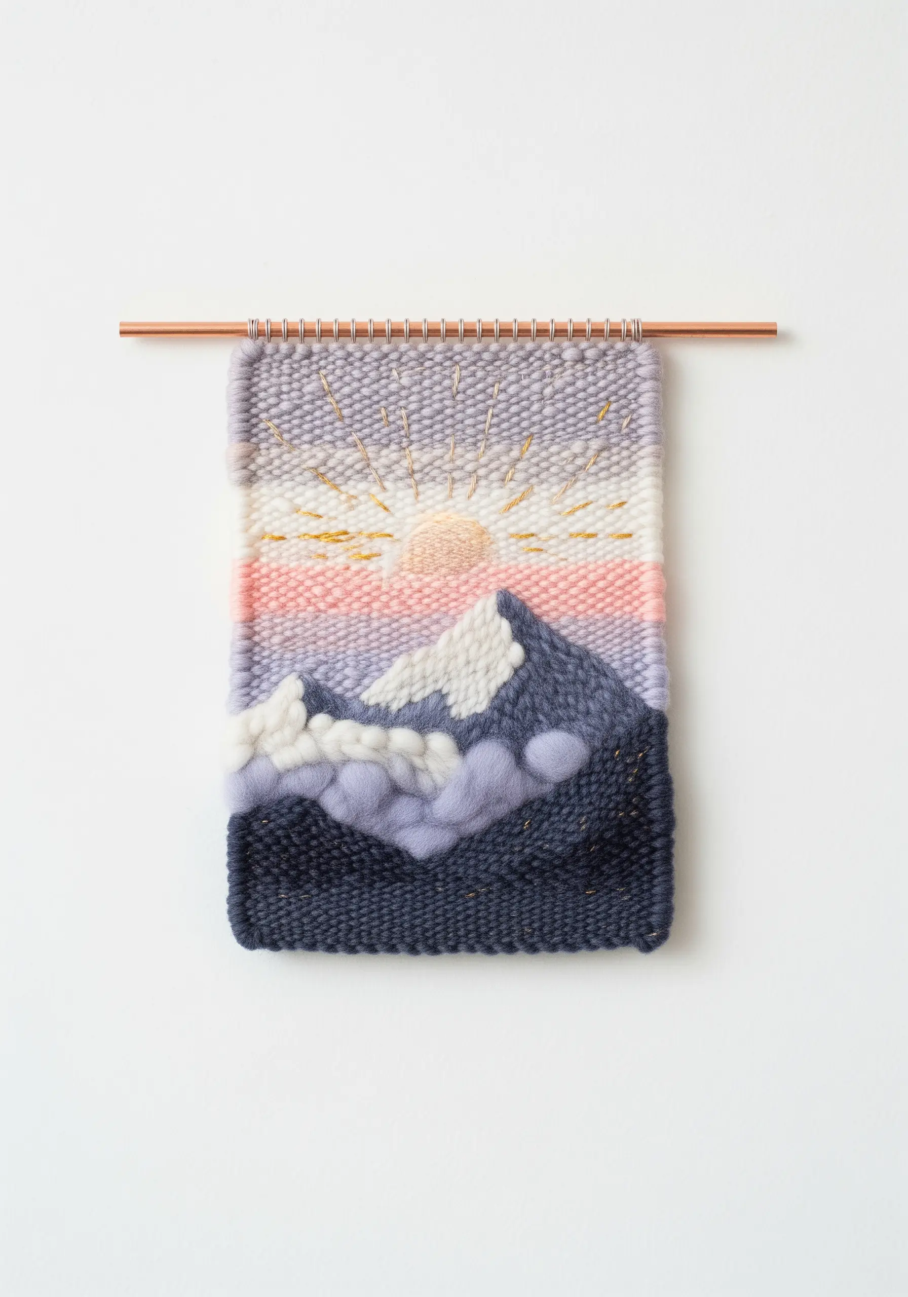 Woven wall hanging of a mountain sunrise with chunky yarn clouds and embroidered sun rays.