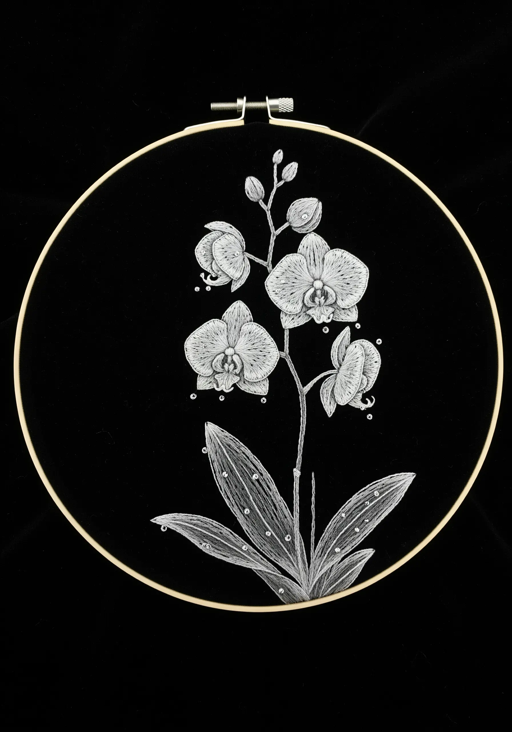 A delicate white-thread embroidery of an orchid, resembling an ink drawing on black fabric.