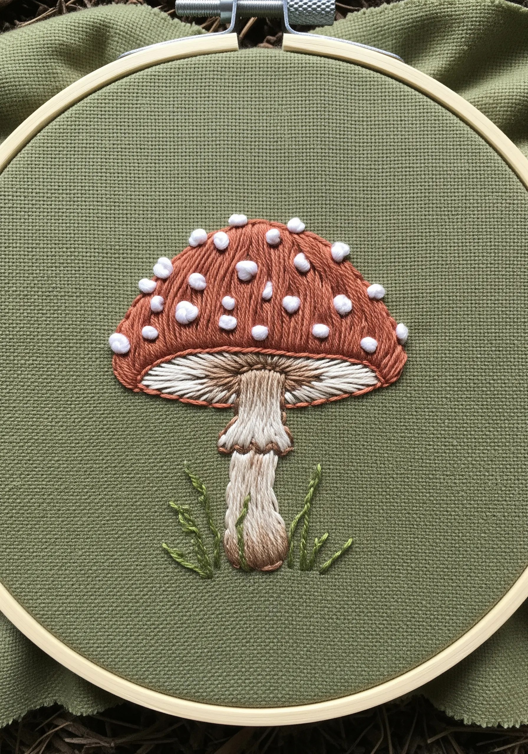 Detailed embroidered toadstool with padded satin stitch spots and shaded cap.