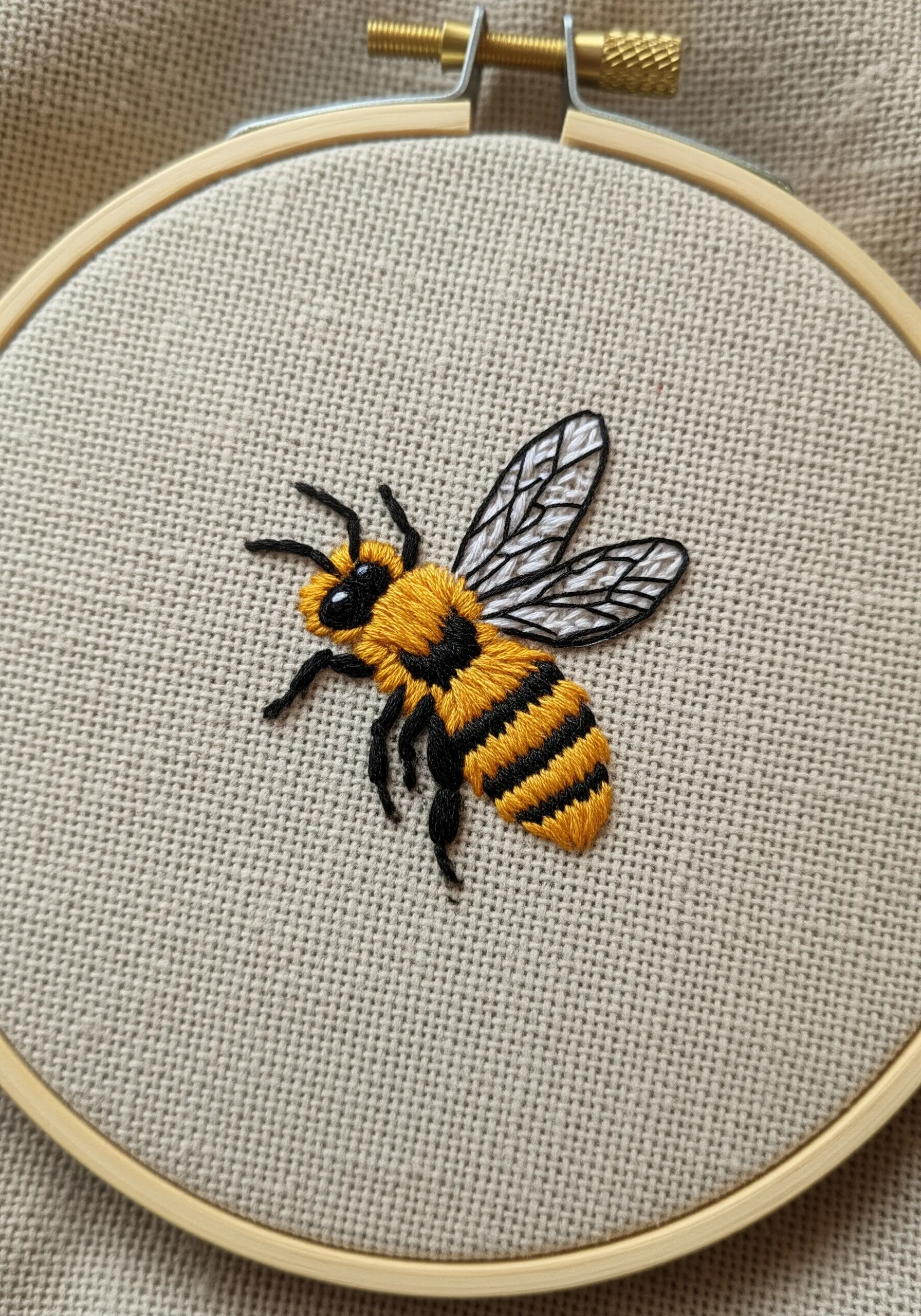 A detailed embroidered bee with fuzzy texture and delicate sheer wings.