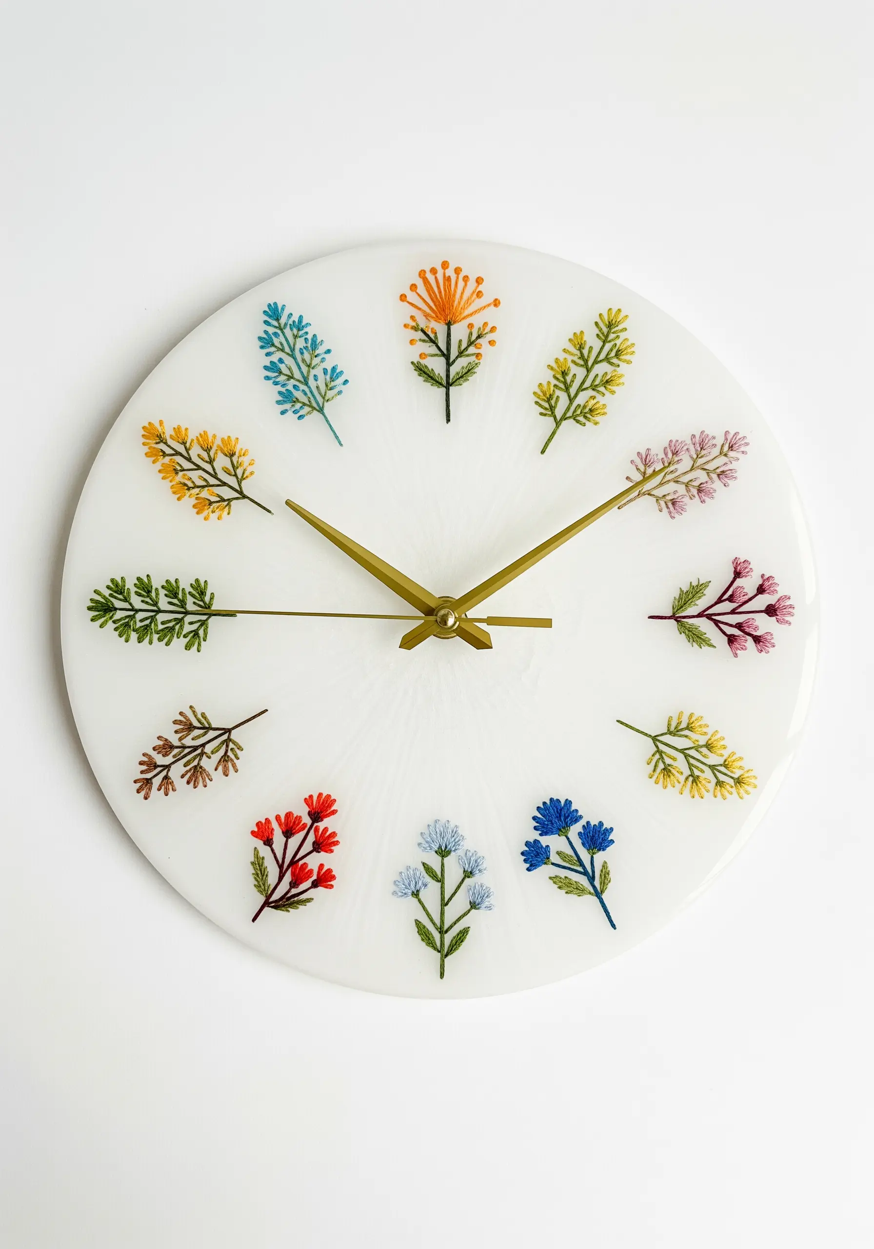 A white resin clock face with twelve different embroidered flowers and leaves marking the hours.