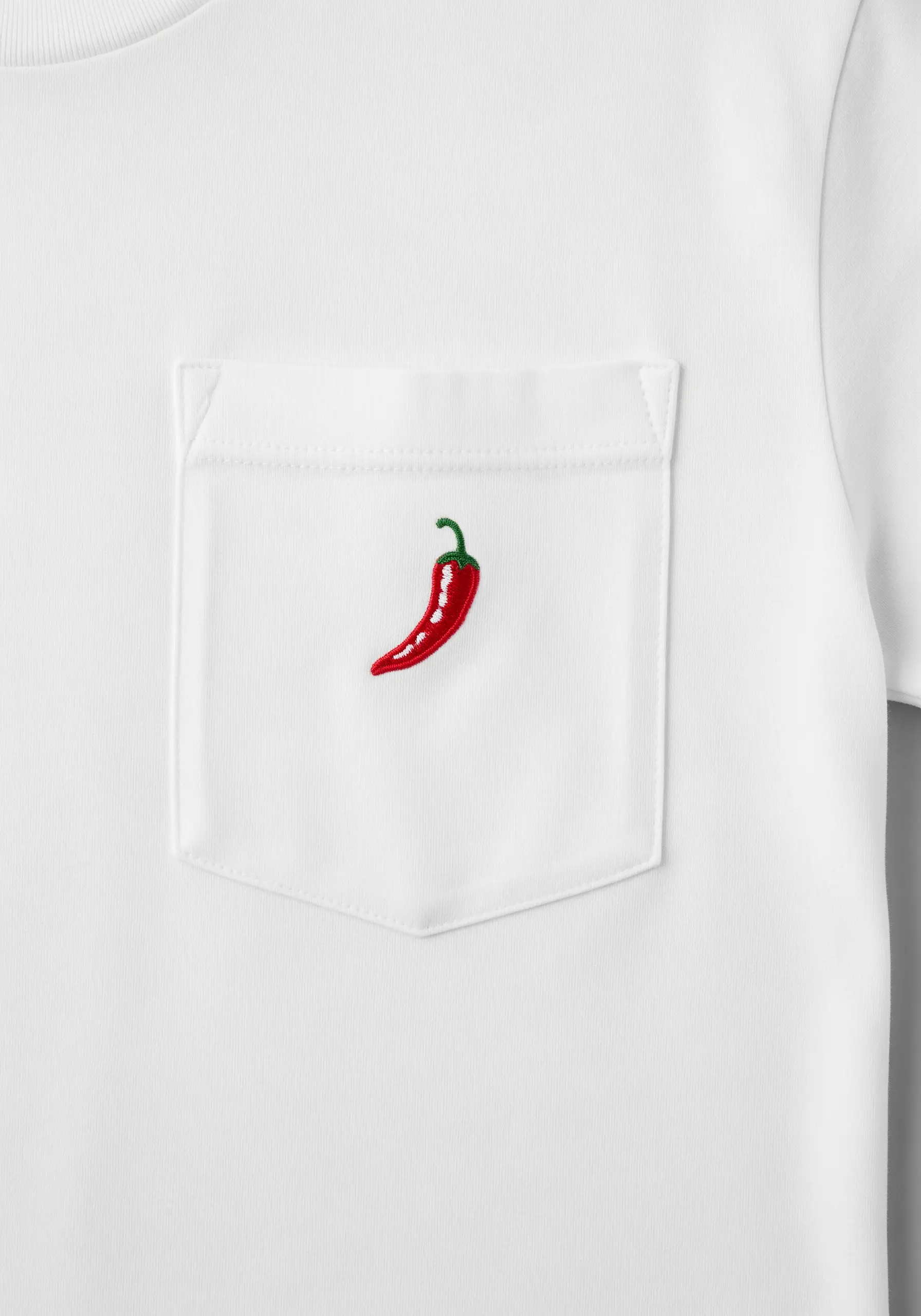 A shiny red chili pepper with a green stem embroidered on a t-shirt pocket.