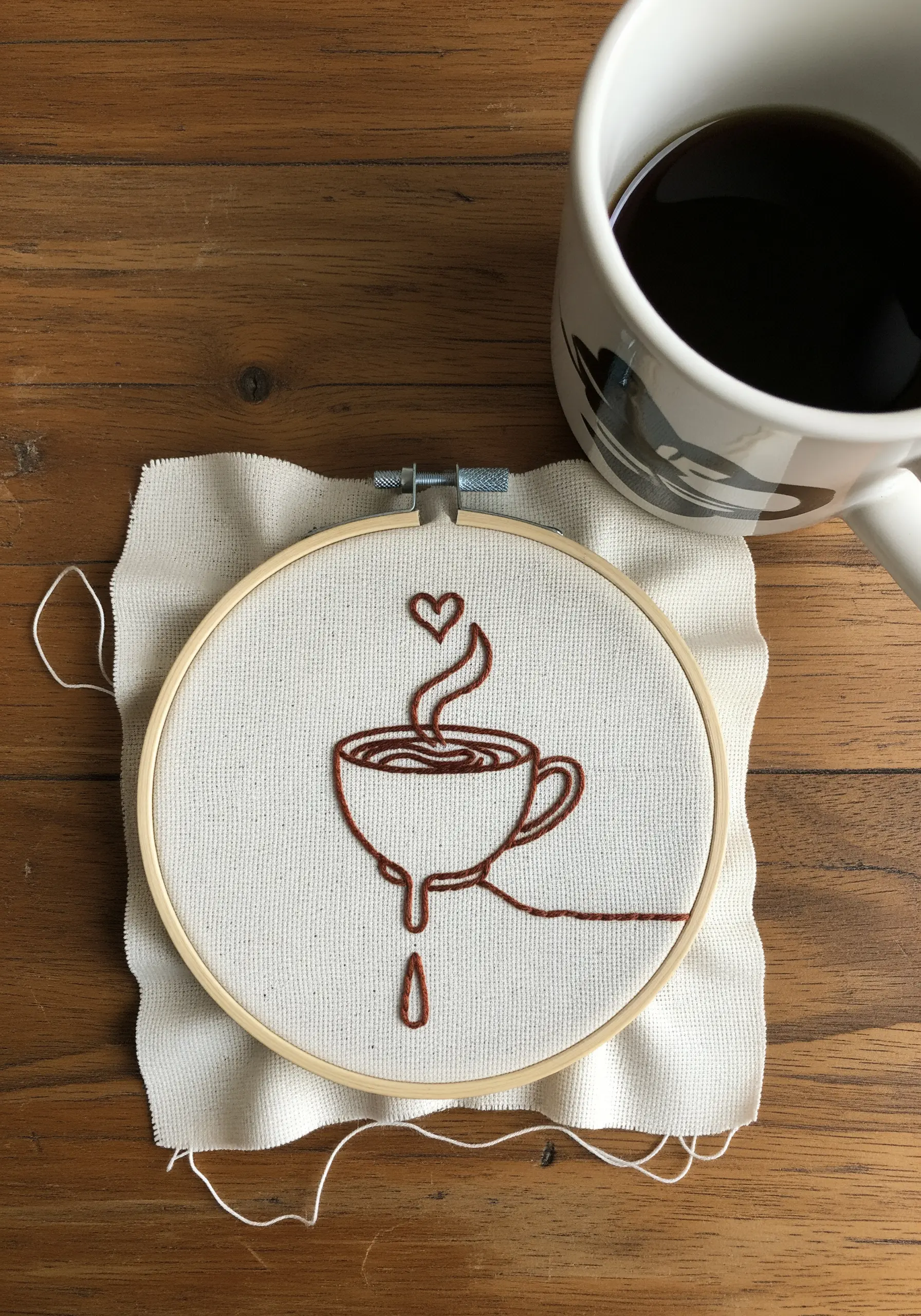 A line art embroidery of a steaming coffee cup with a single drip falling.