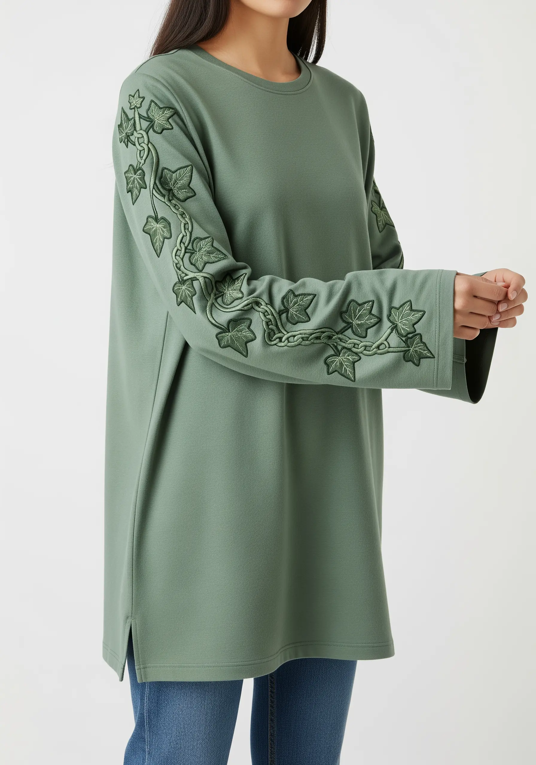 A chain-stitched ivy vine with leaves wrapping down the long sleeve of a green tunic.