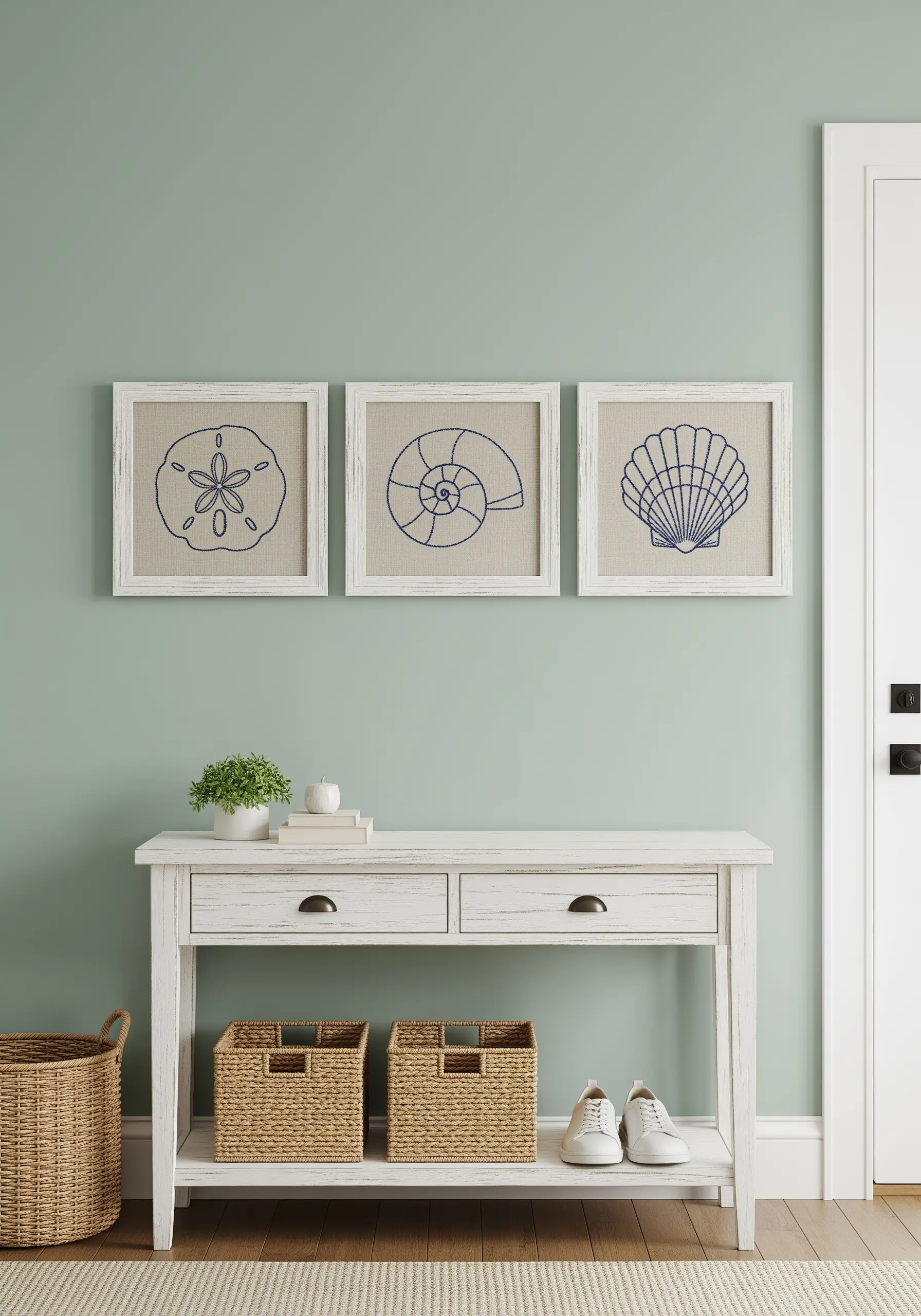 A triptych of framed embroidery pieces, each featuring a different seashell stitched in blue.