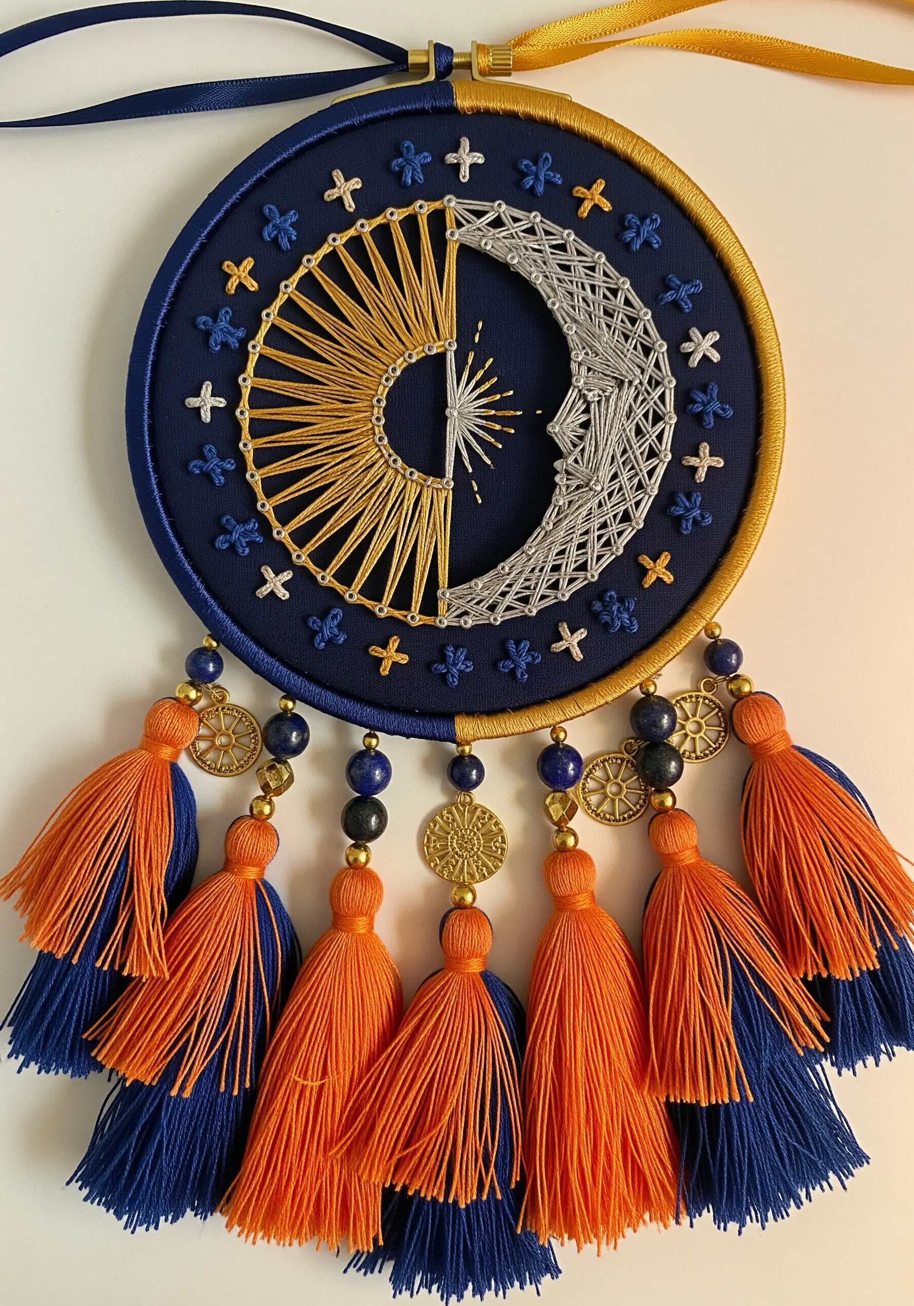Half-sun, half-moon string art dreamcatcher in gold, silver, and navy blue.