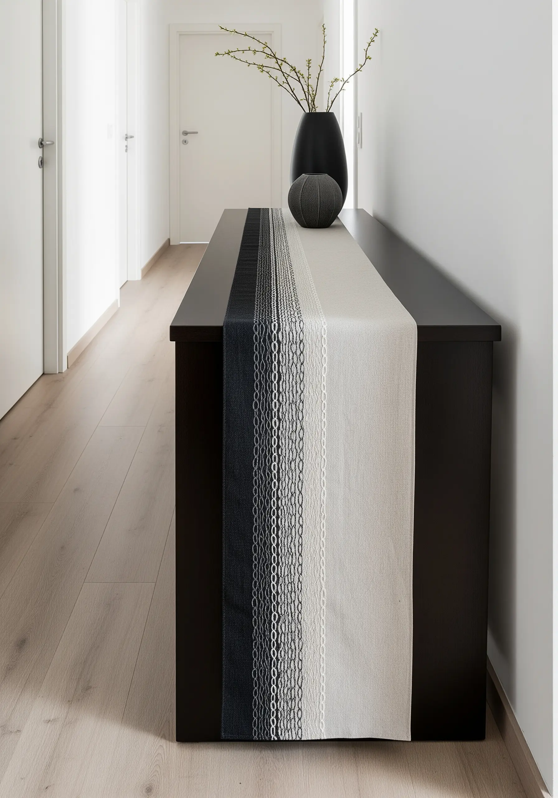 A table runner with vertical stripes of chain stitch in a gradient from black to grey to white.