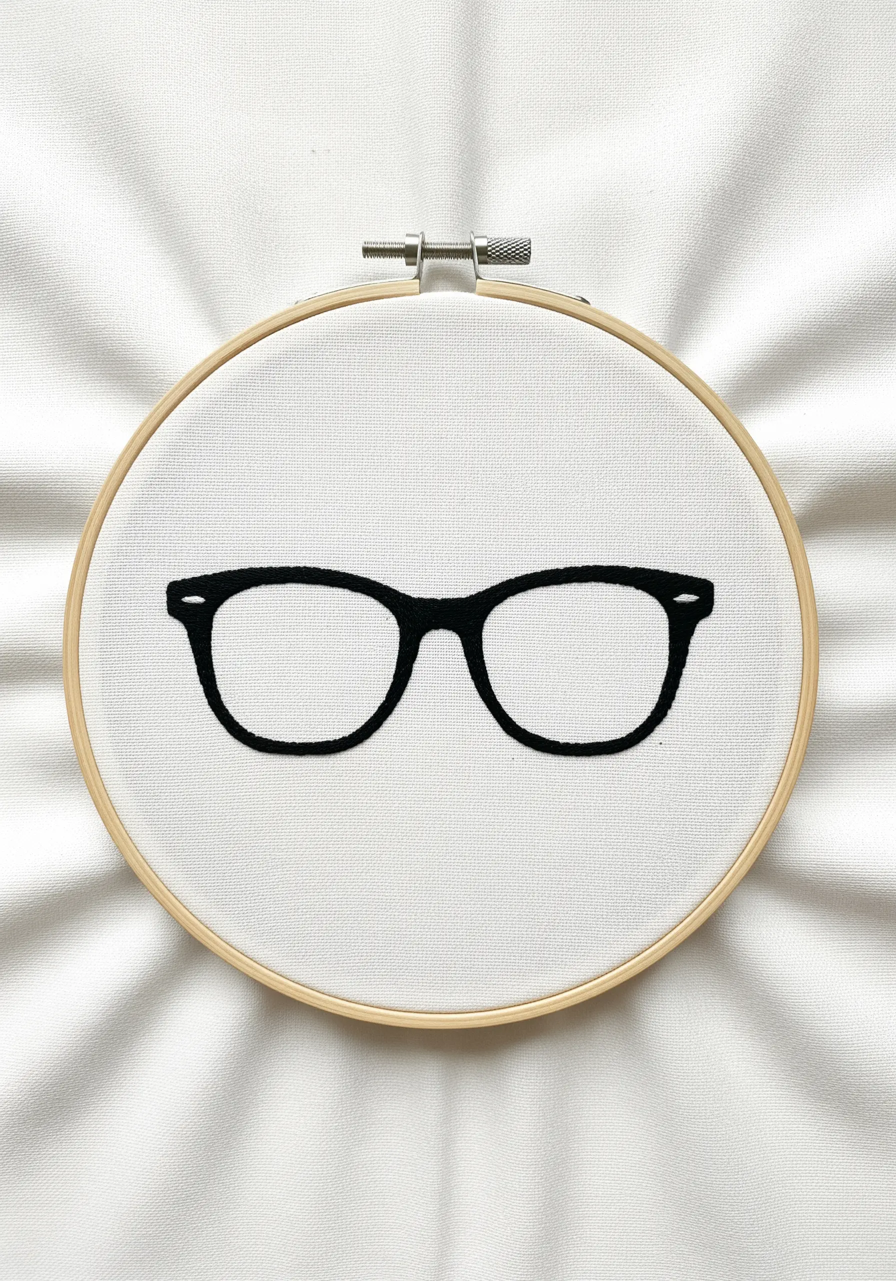 A pair of black-rimmed eyeglasses filled with a solid, smooth satin stitch.
