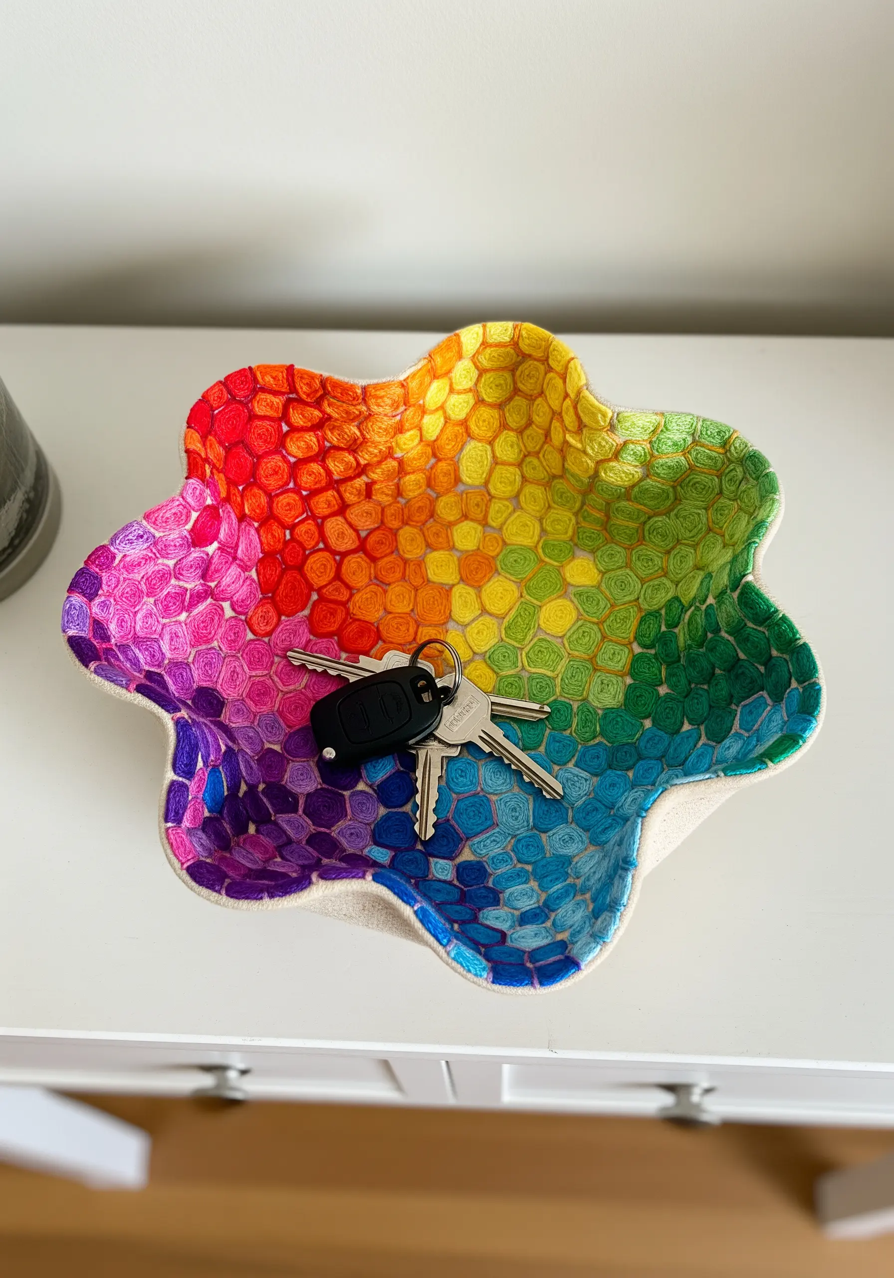 A colorful, flower-shaped catch-all bowl made from embroidered fabric hardened into shape.