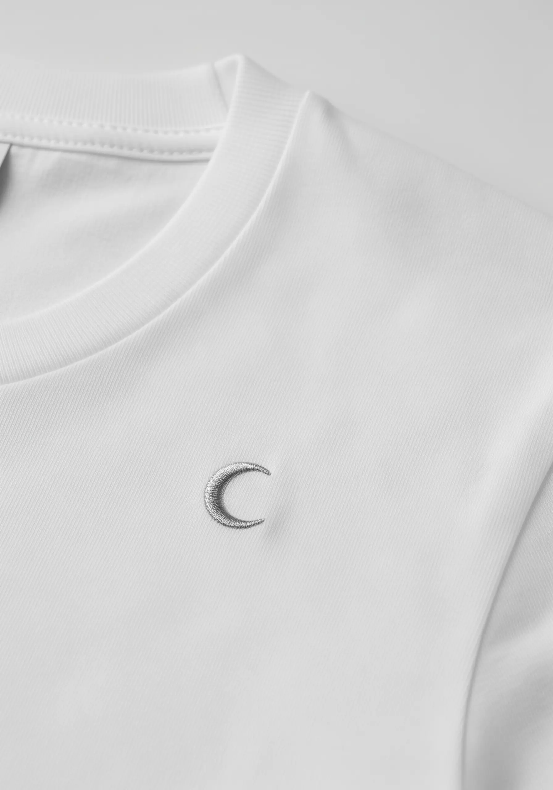 A crescent moon embroidered with light and dark gray thread for a shaded effect.