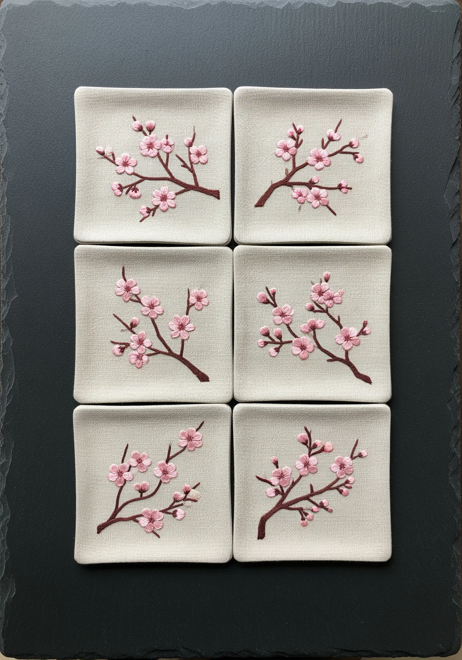 A set of six embroidered linen coasters, each with a unique cherry blossom design.