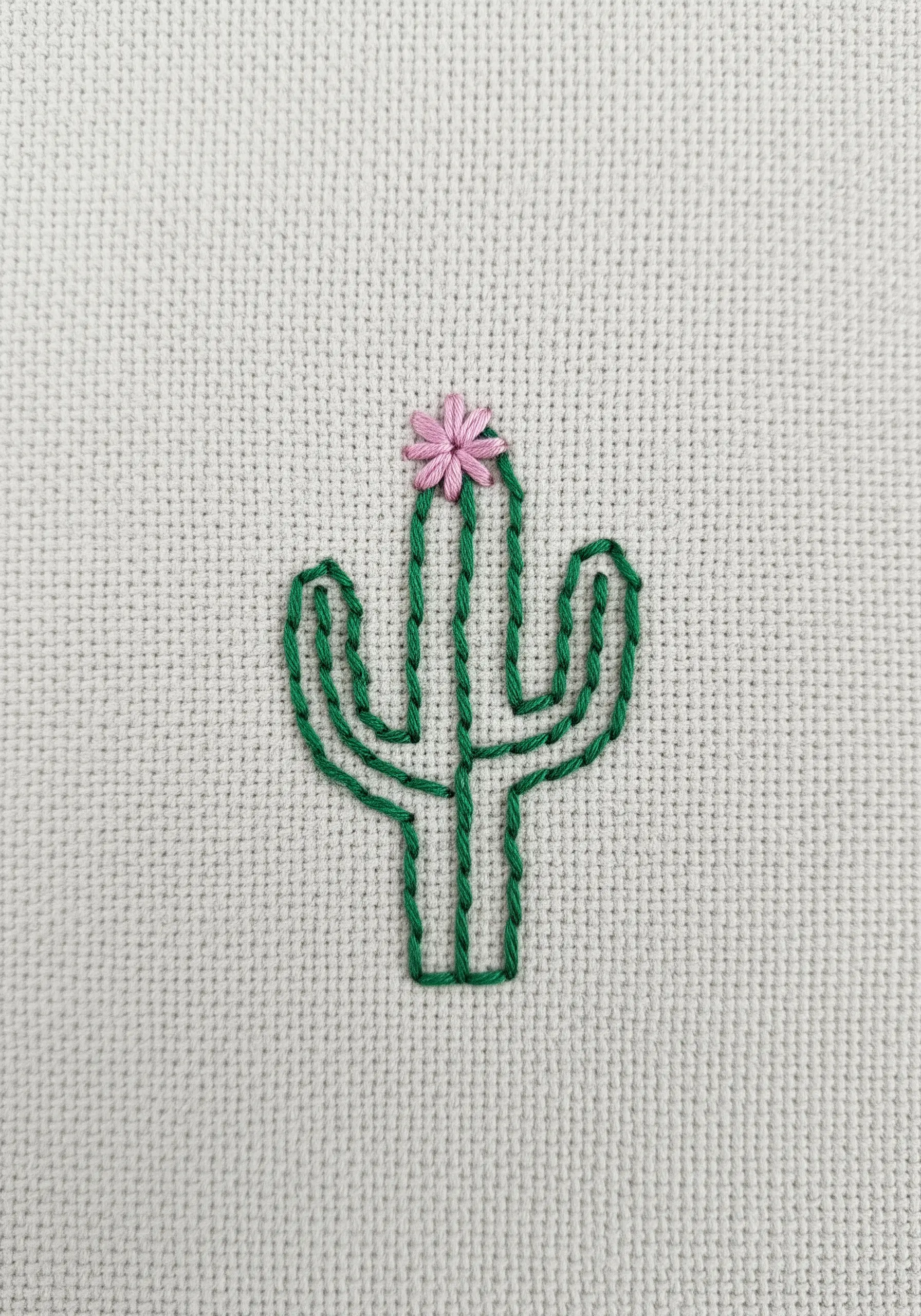 A minimalist green outline of a saguaro cactus with a small pink flower on top.