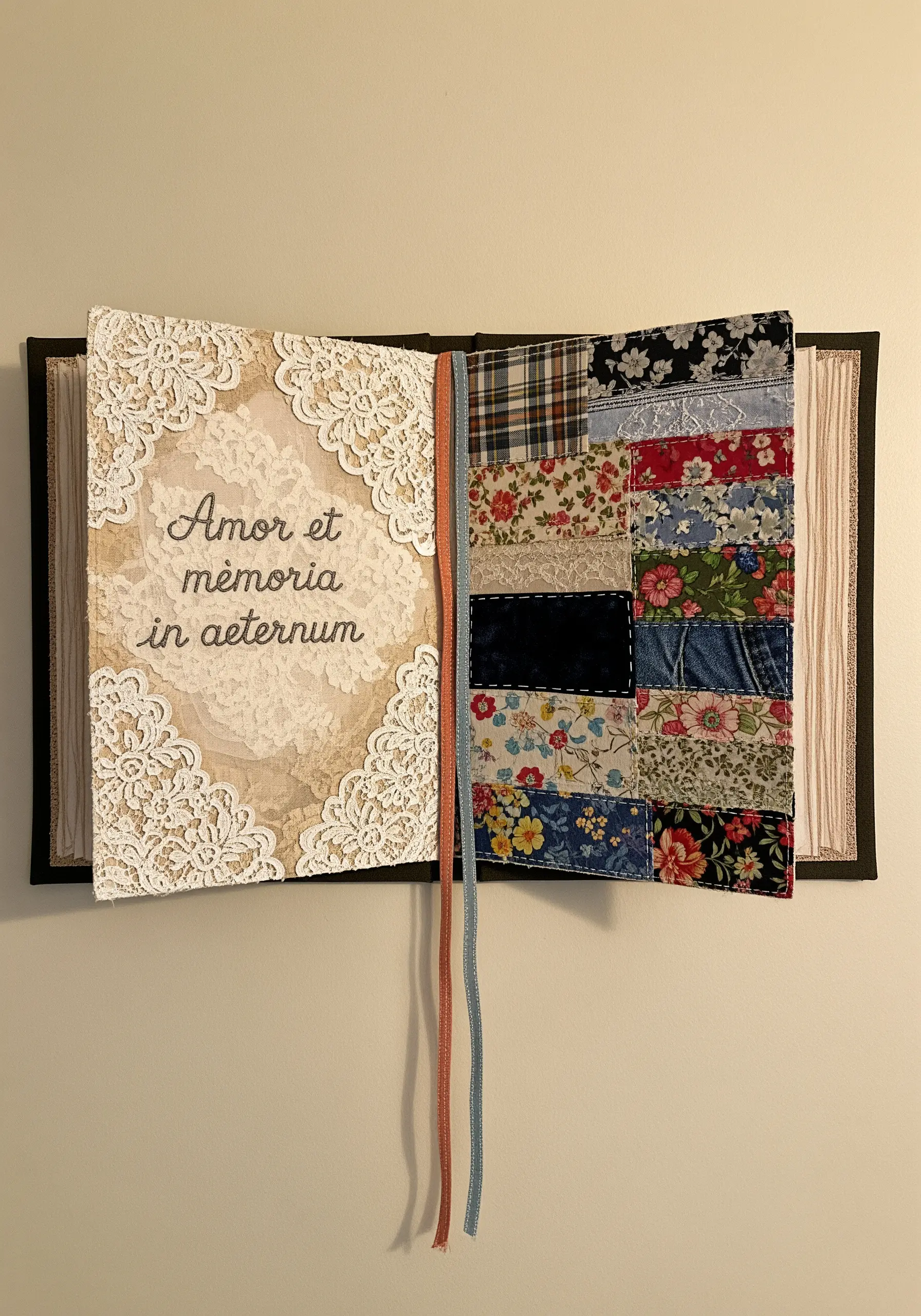 A wall art piece shaped like an open book, with lace and script on one side and patchwork on the other.