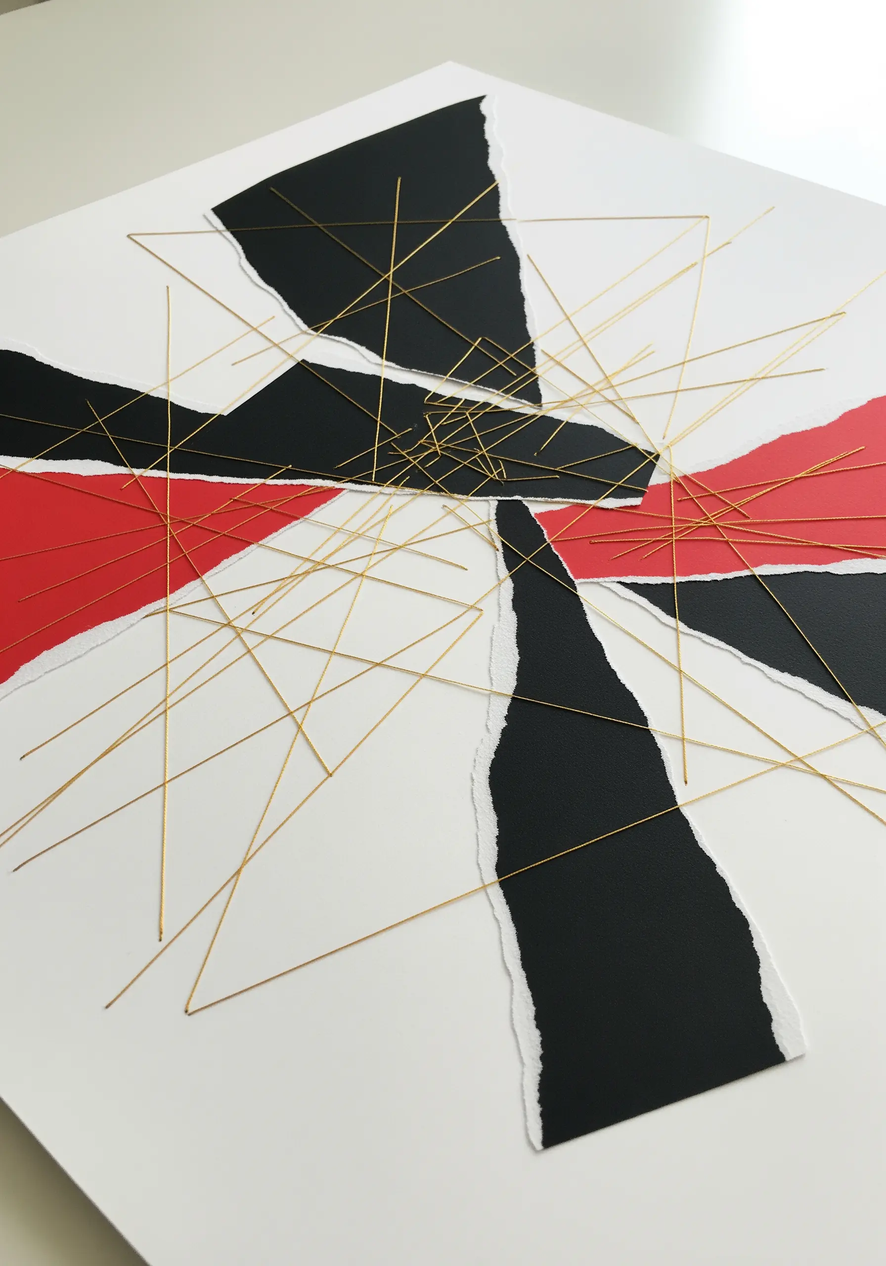 Abstract collage of torn paper with a web of straight, intersecting gold threads stretched over it.