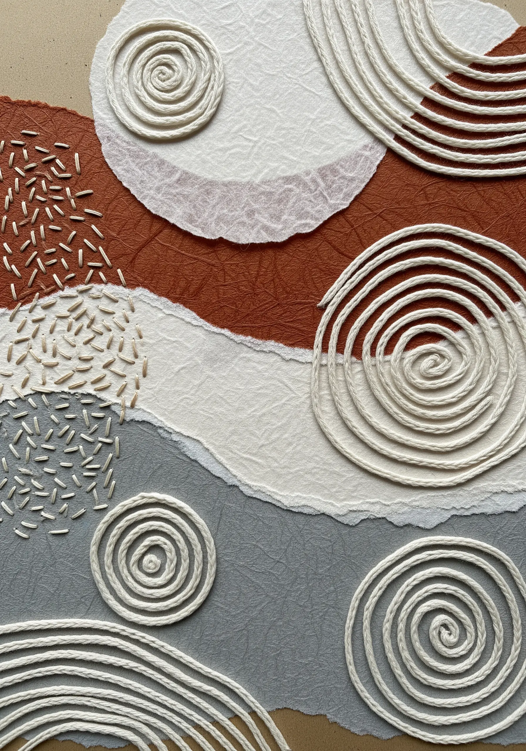 An abstract textural collage with couched yarn spirals and areas of dense seed stitch.