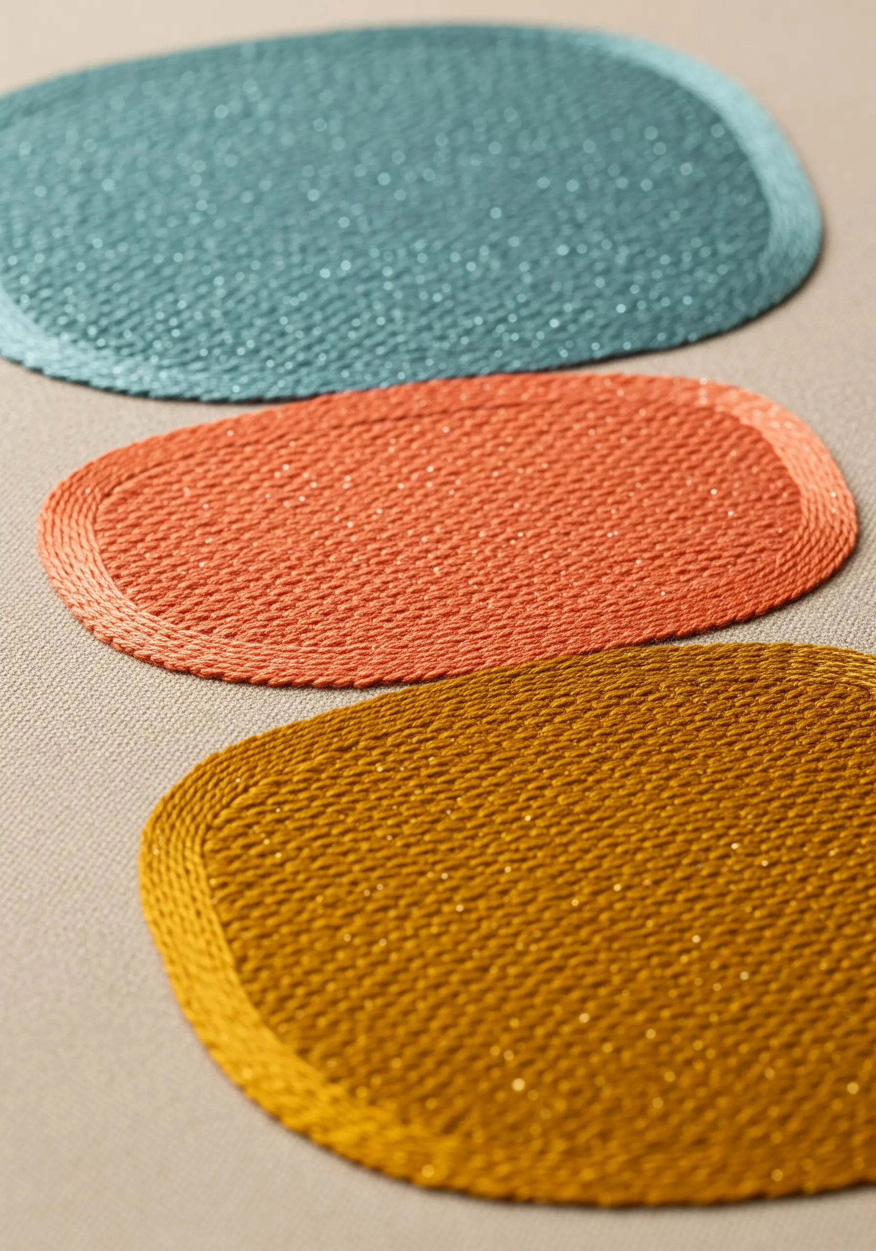 Three abstract oval shapes embroidered in teal orange and mustard