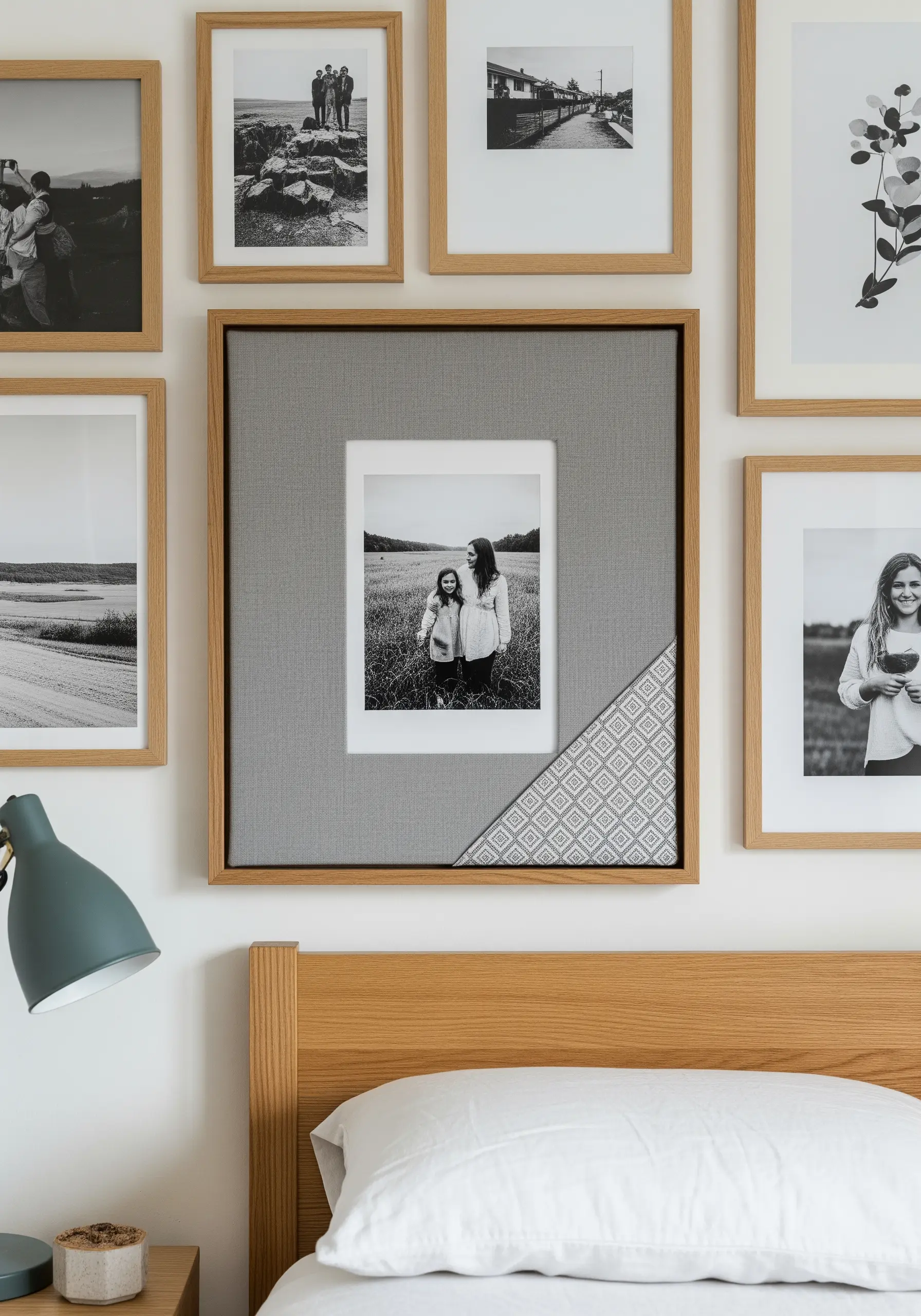 A framed photo with a wide grey fabric mat, accented with a small, geometric embroidered pattern in the corner.