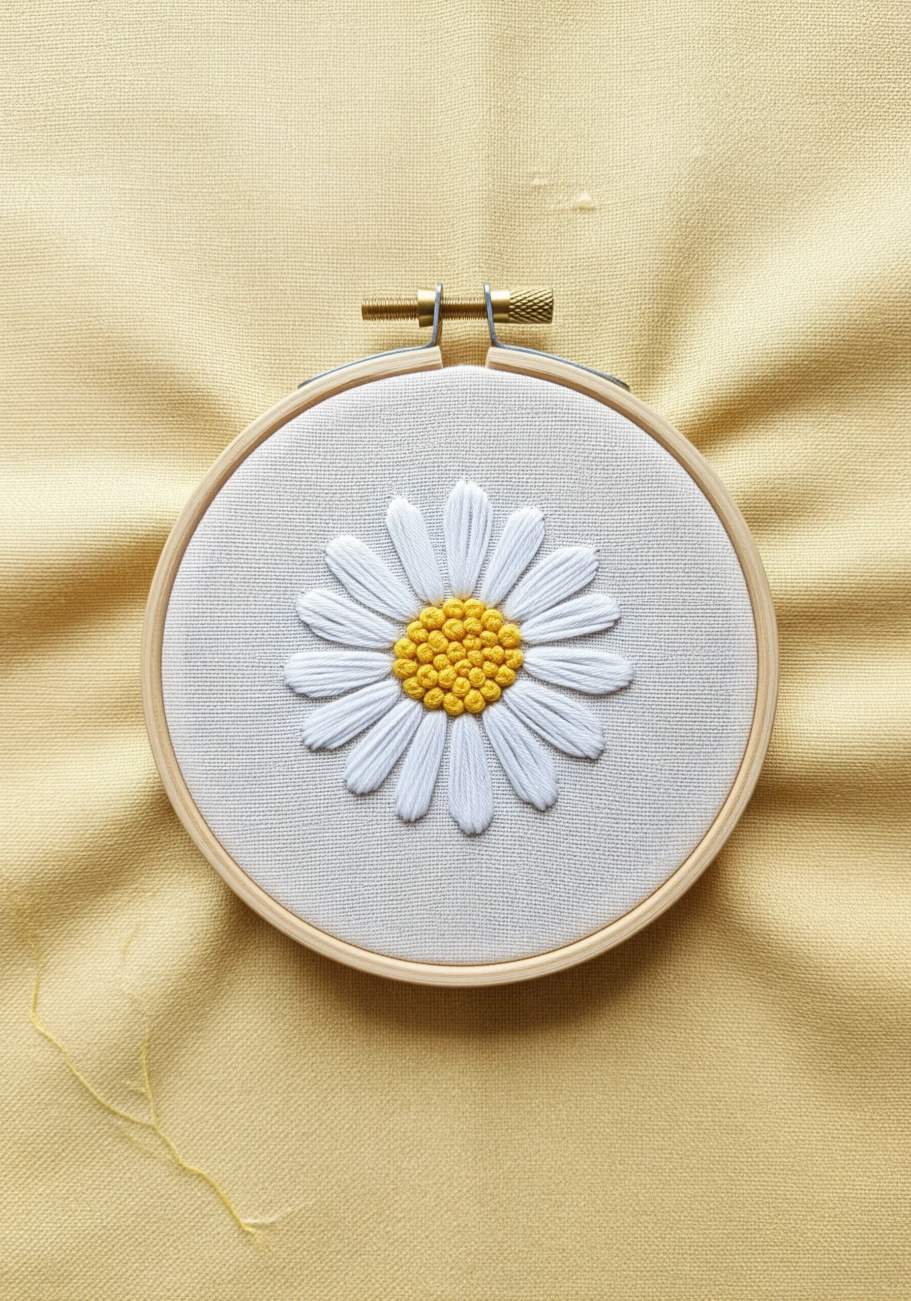 A classic daisy with white satin-stitched petals and a yellow French knot center.