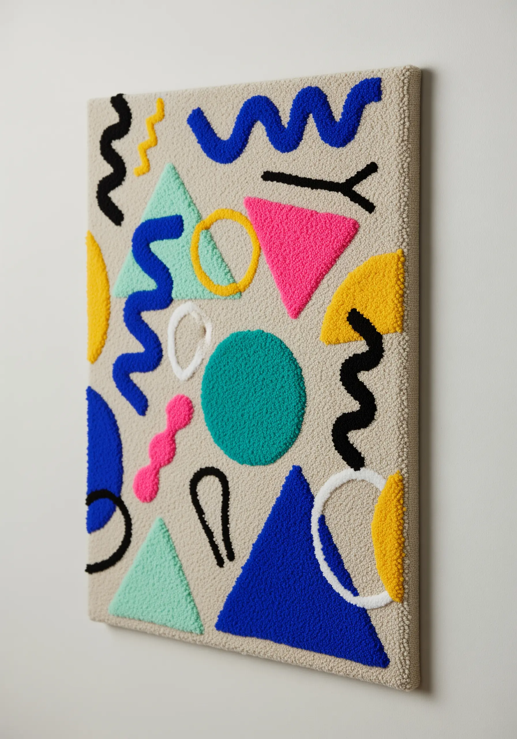 Tufted wall art with colorful abstract shapes reminiscent of Memphis design on a neutral background.