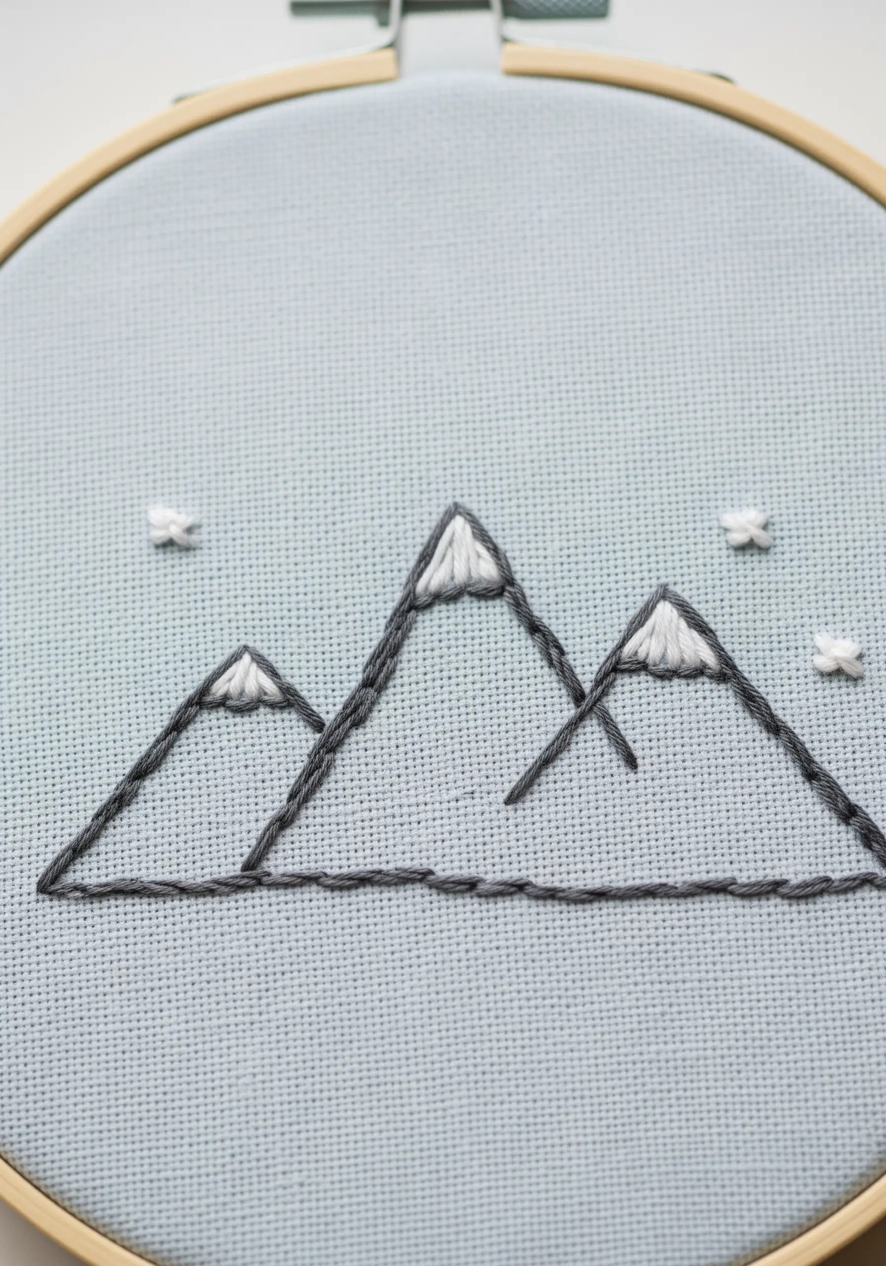 Minimalist embroidered mountains with bold outlines and satin-stitched snowcaps.