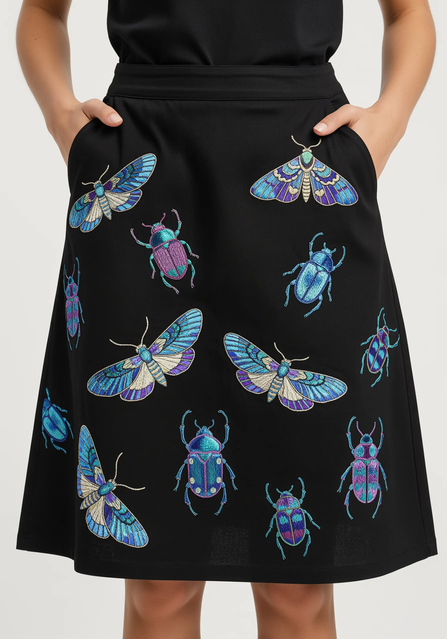 A pattern of iridescent blue and purple embroidered beetles and moths on a black skirt.