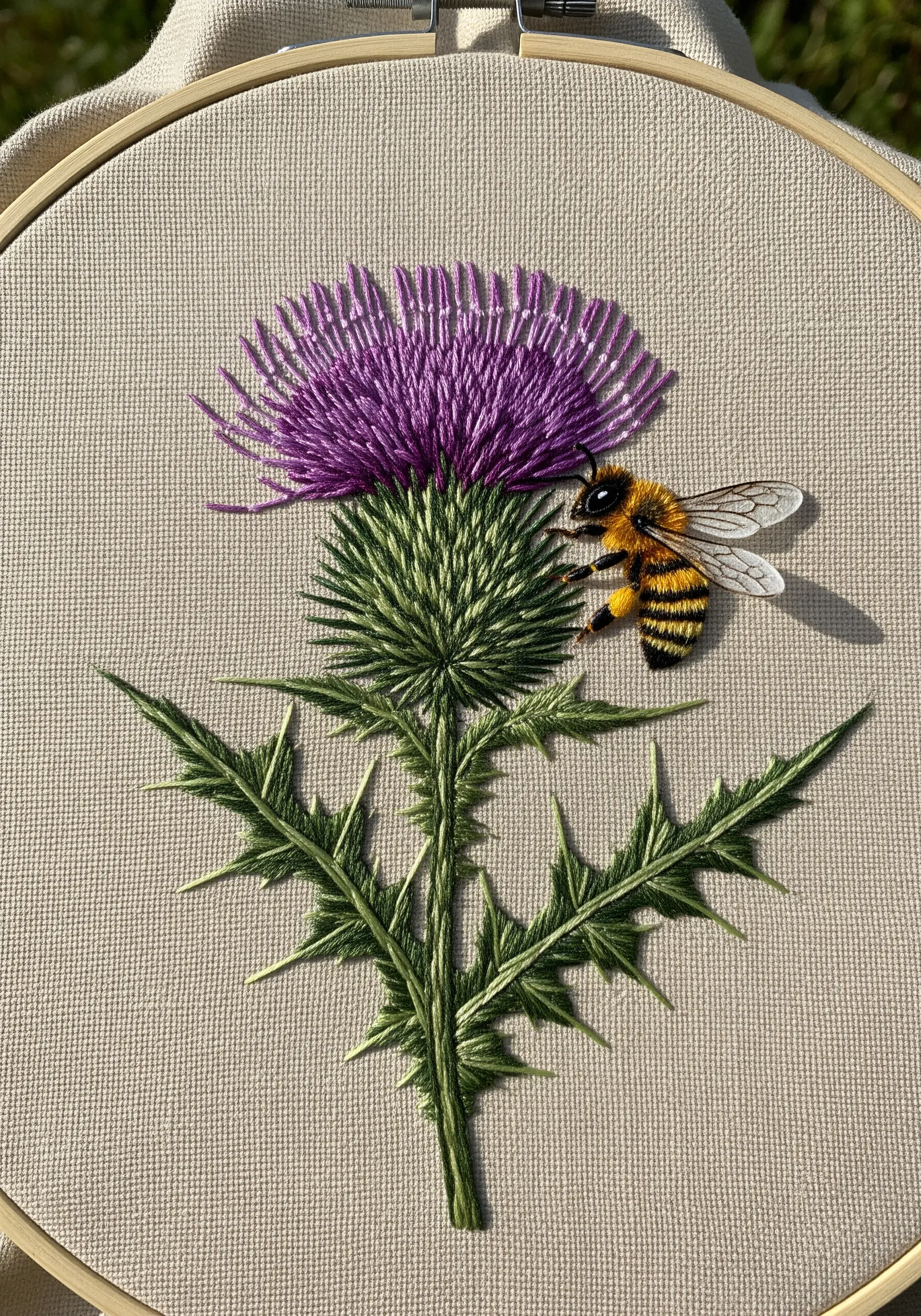 A highly realistic embroidered bee rests on a purple and green thistle.