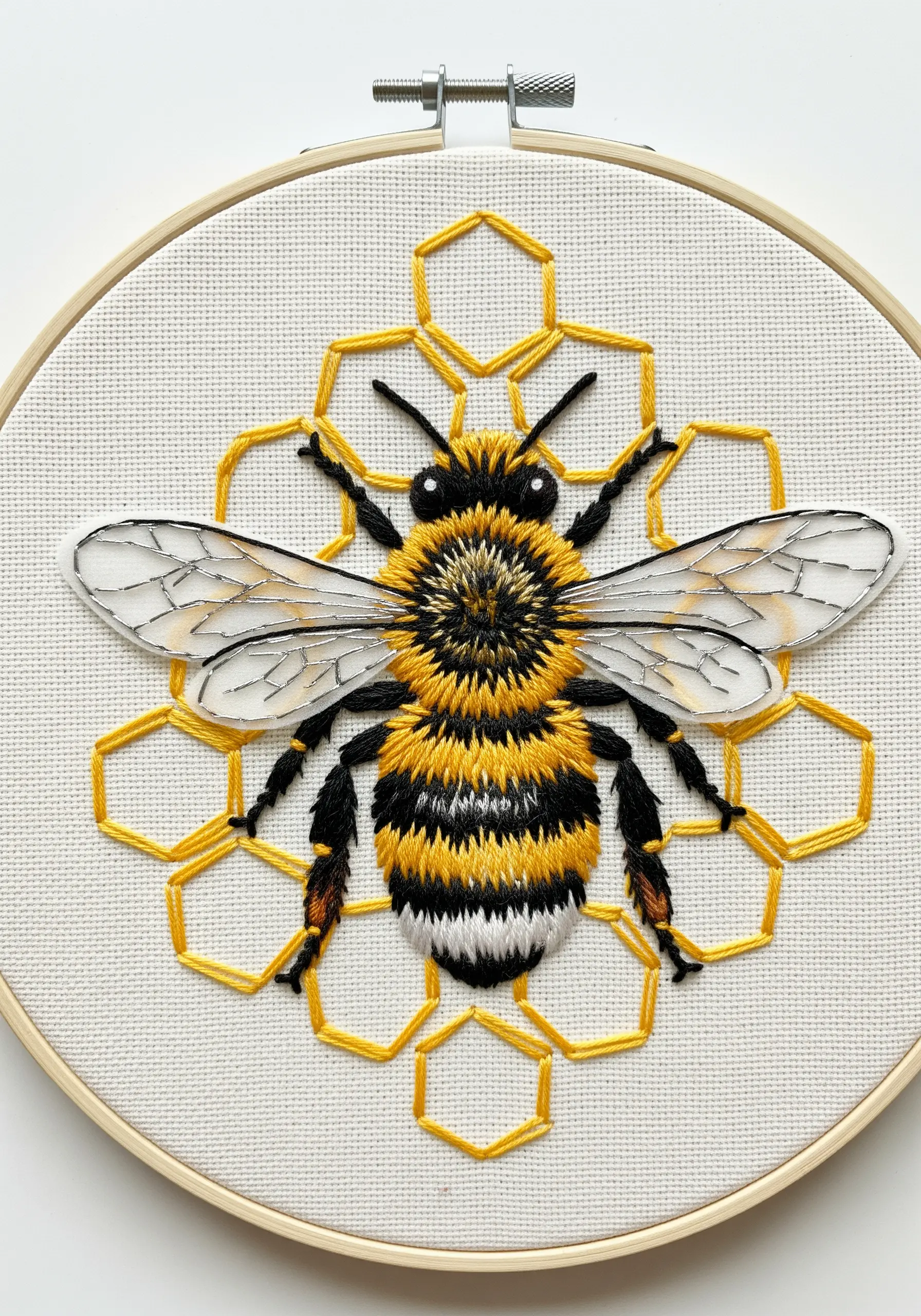 A detailed embroidered bee with fuzzy texture on a geometric honeycomb background.
