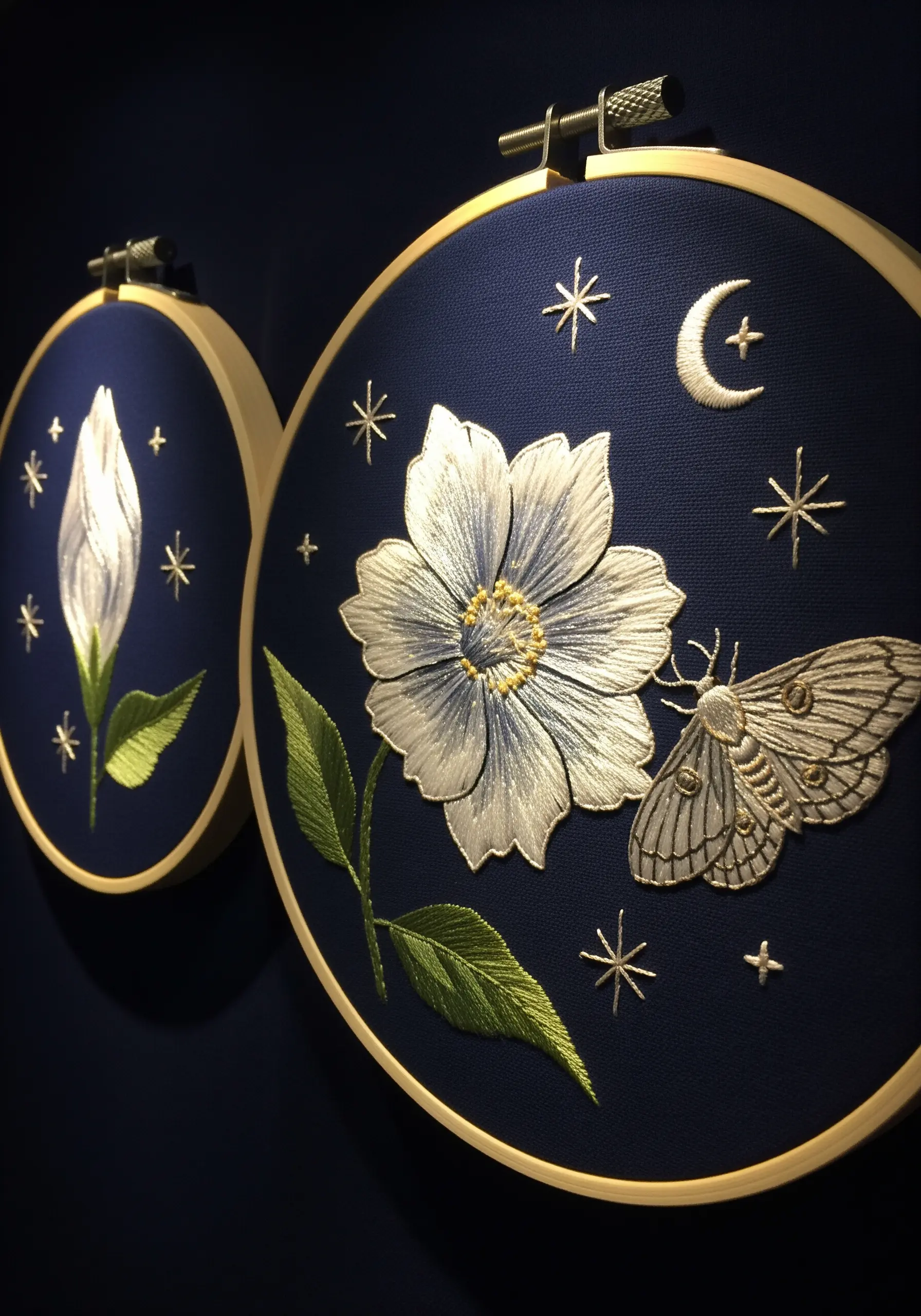 A night-blooming flower and moth stitched in white and silver on navy blue fabric.