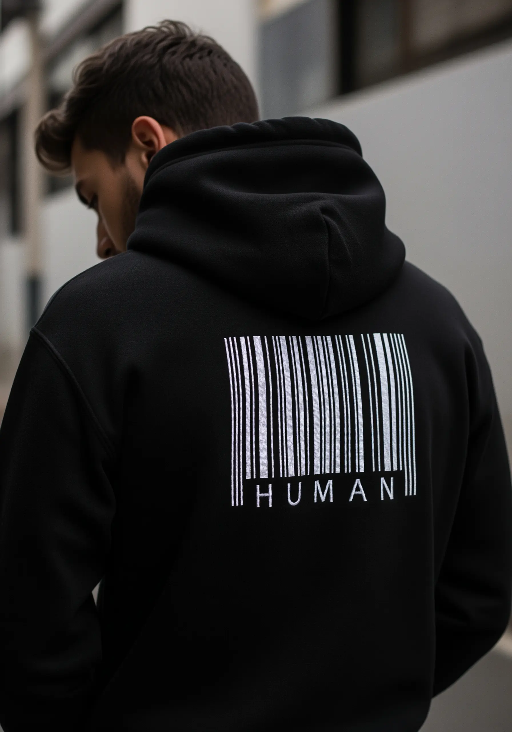 A barcode with the word 'HUMAN' embroidered in white on the back of a black hoodie.