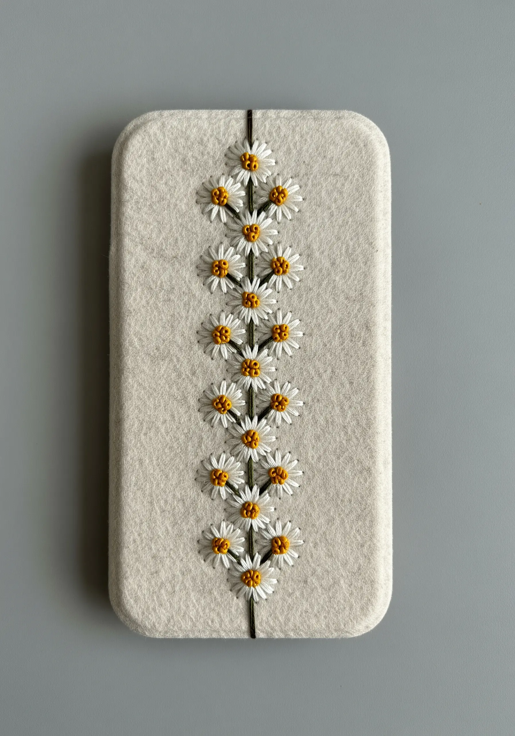 Symmetrical column of tiny embroidered daisies on a light gray felt phone case.