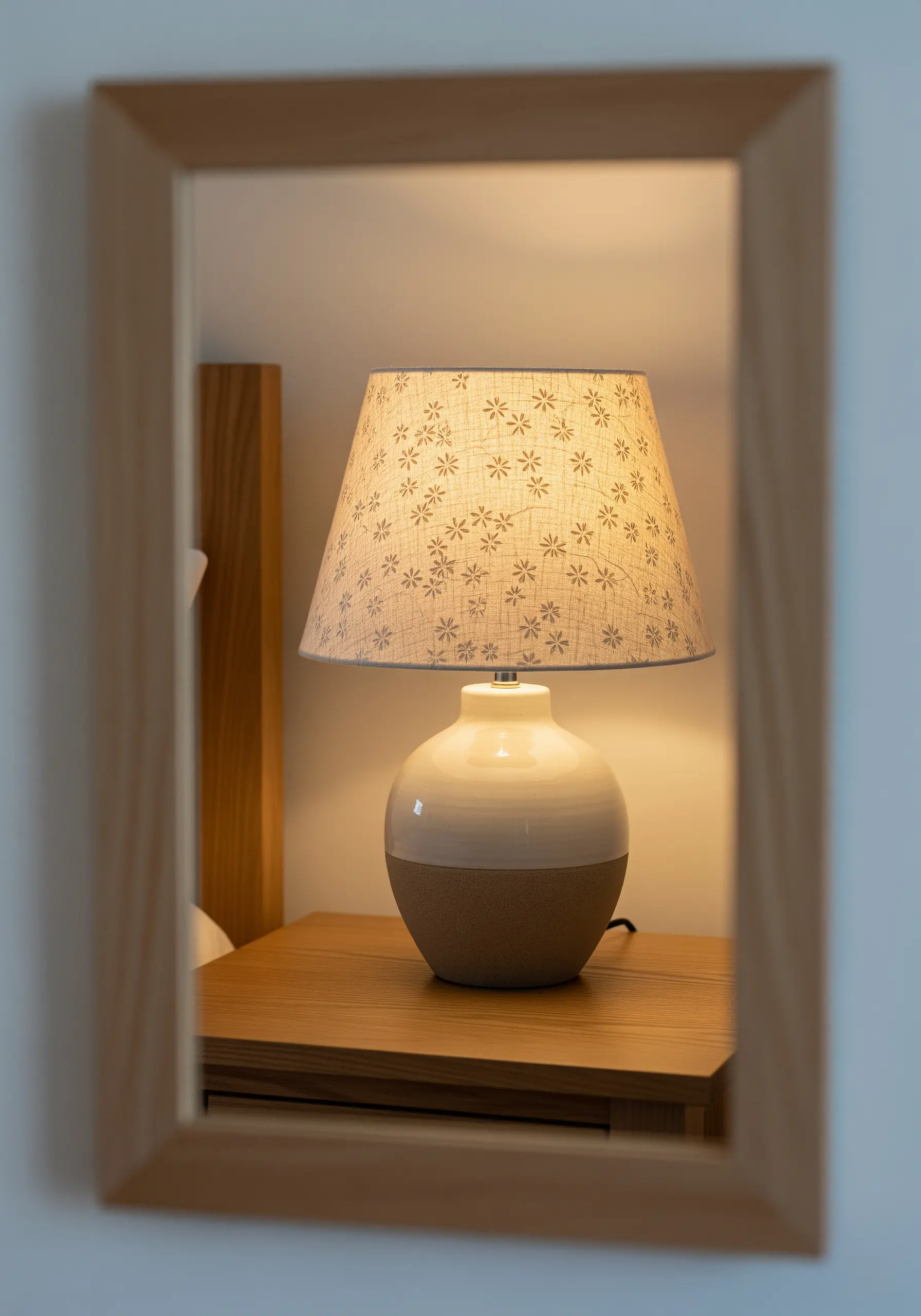 A close-up of a fabric lampshade with a subtle, repeating floral stitch pattern.