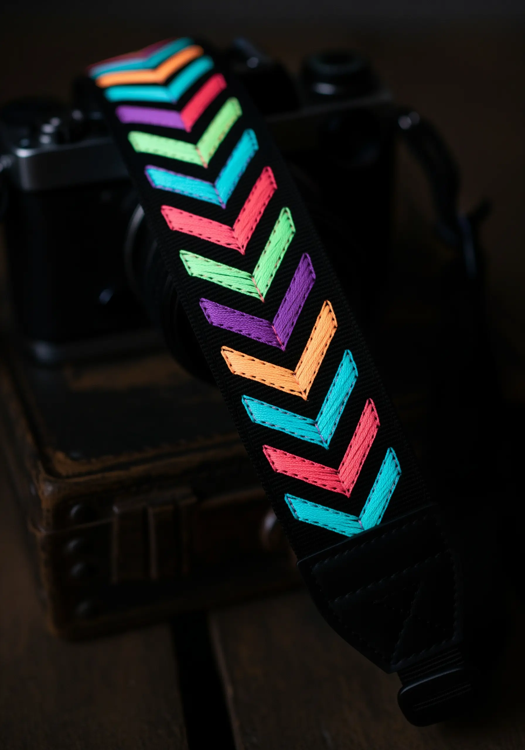 A colorful neon chevron pattern with thin black outlines on a camera strap.