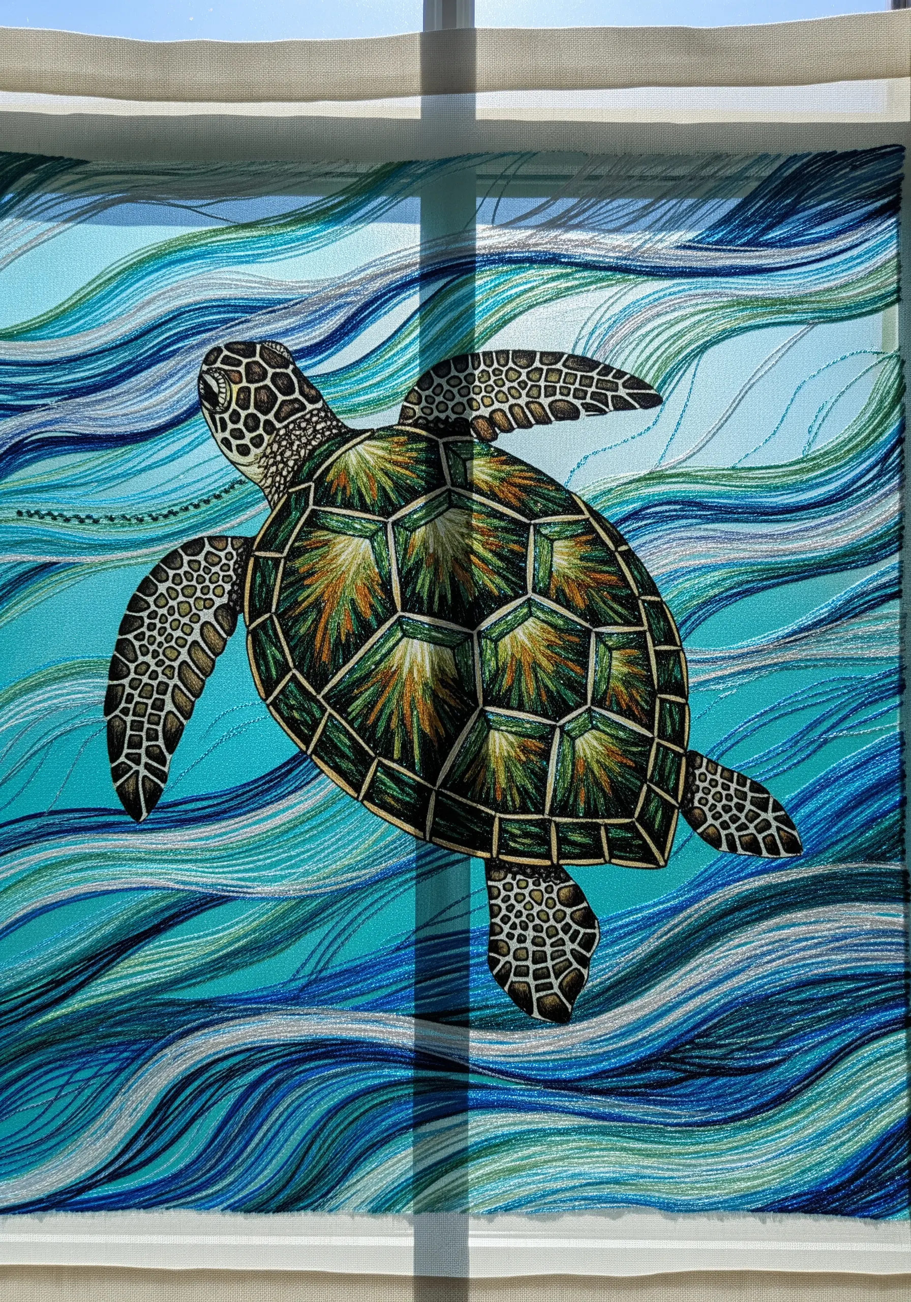 A sea turtle embroidered over a printed fabric background of ocean waves.