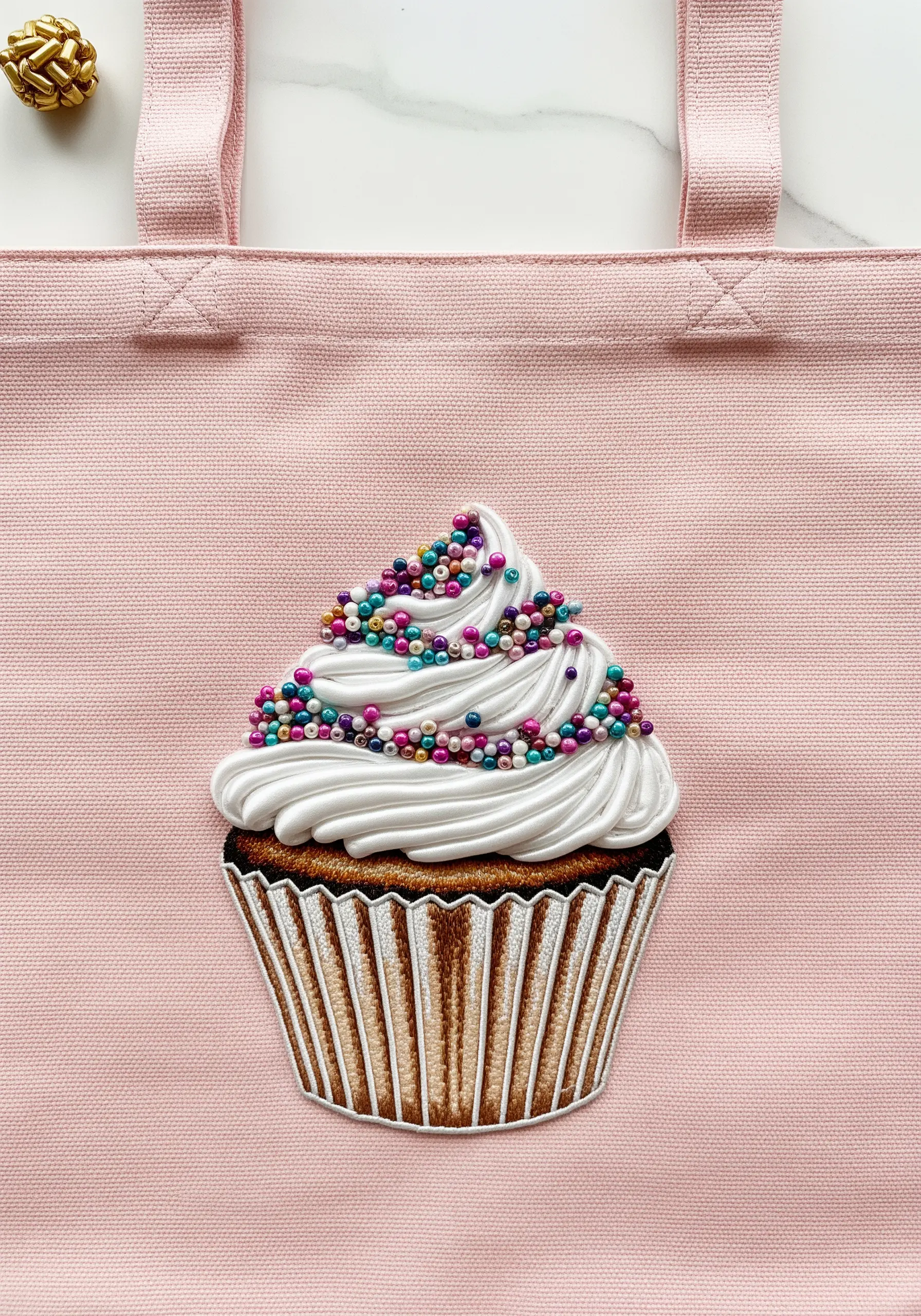 An embroidered cupcake with smooth frosting and colorful seed beads as sprinkles.