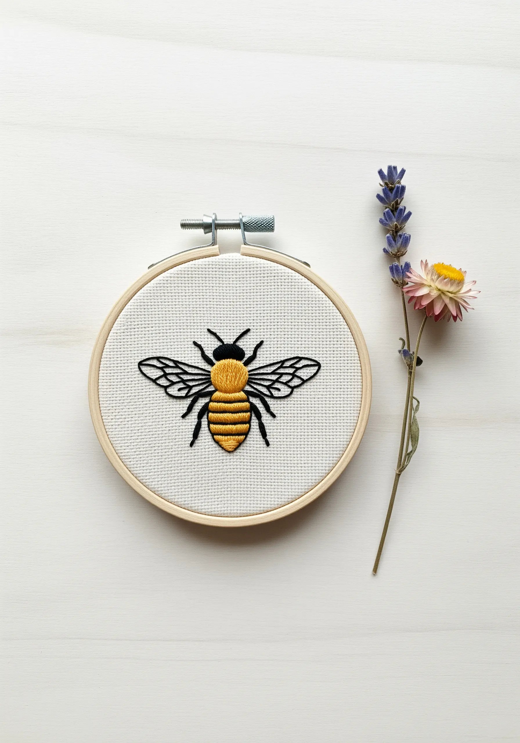 A bee with satin-stitched stripes and delicate backstitched wings in an embroidery hoop.