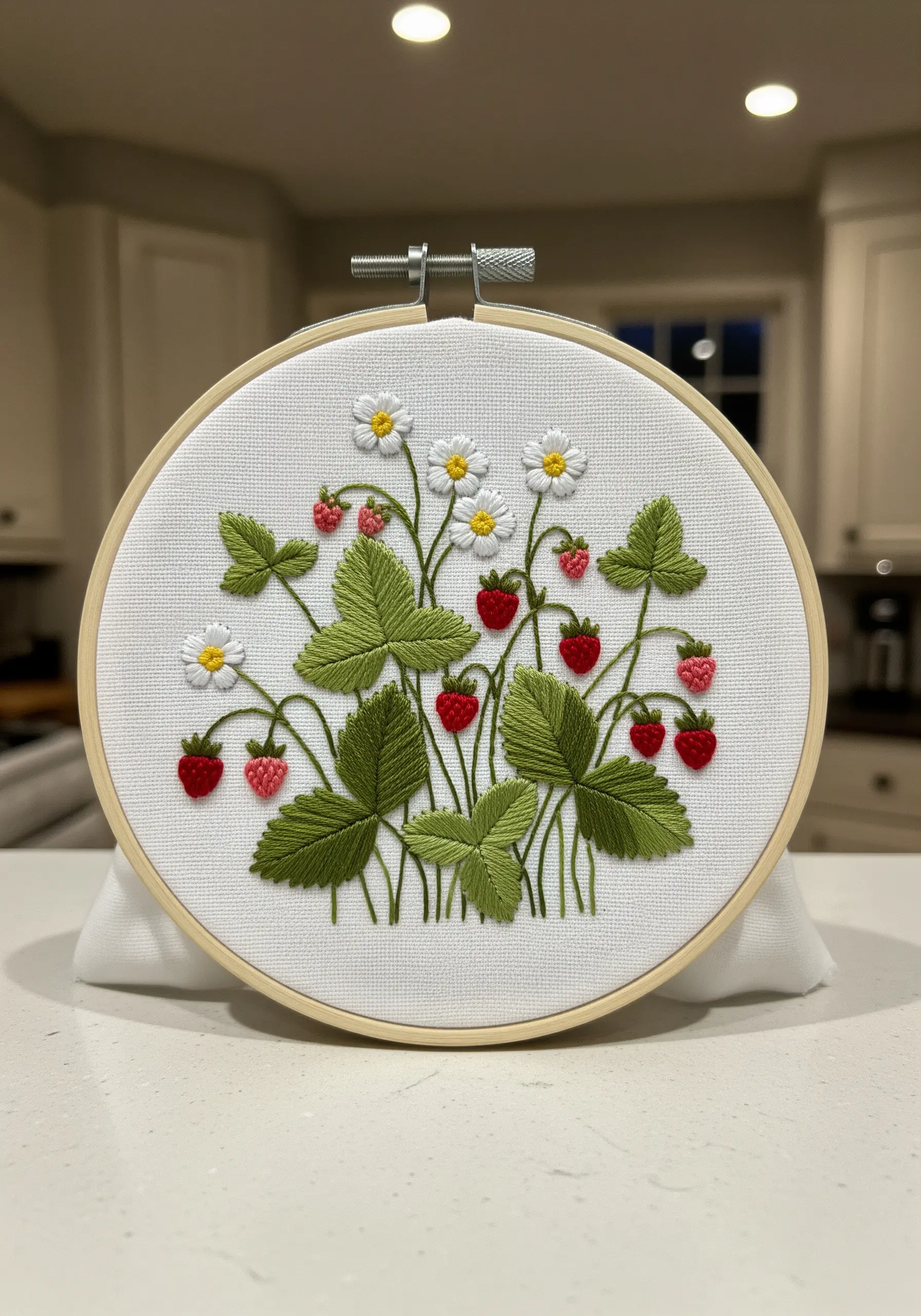Embroidery of wild strawberries with detailed, veined leaves on white fabric.