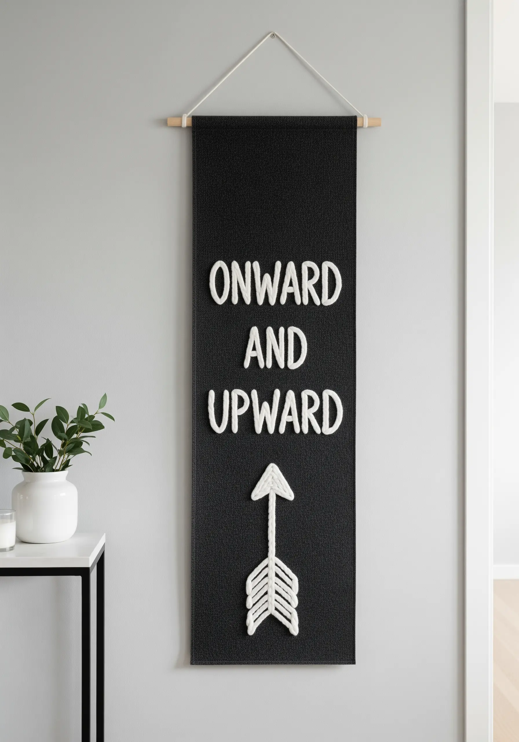 A black wall banner with a motivational quote stitched in thick, white 3D yarn.