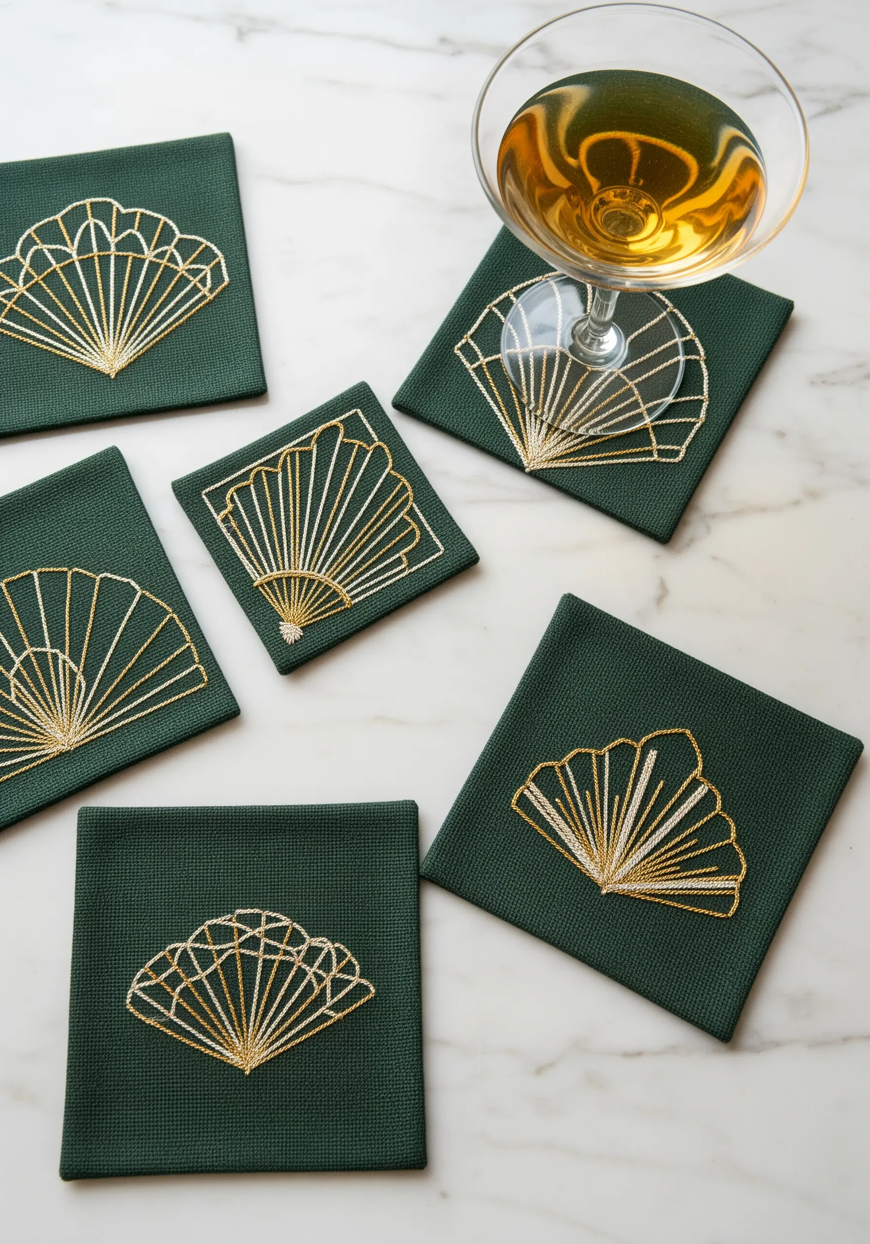 A set of dark green coasters with Art Deco fan patterns stitched in gold metallic thread.