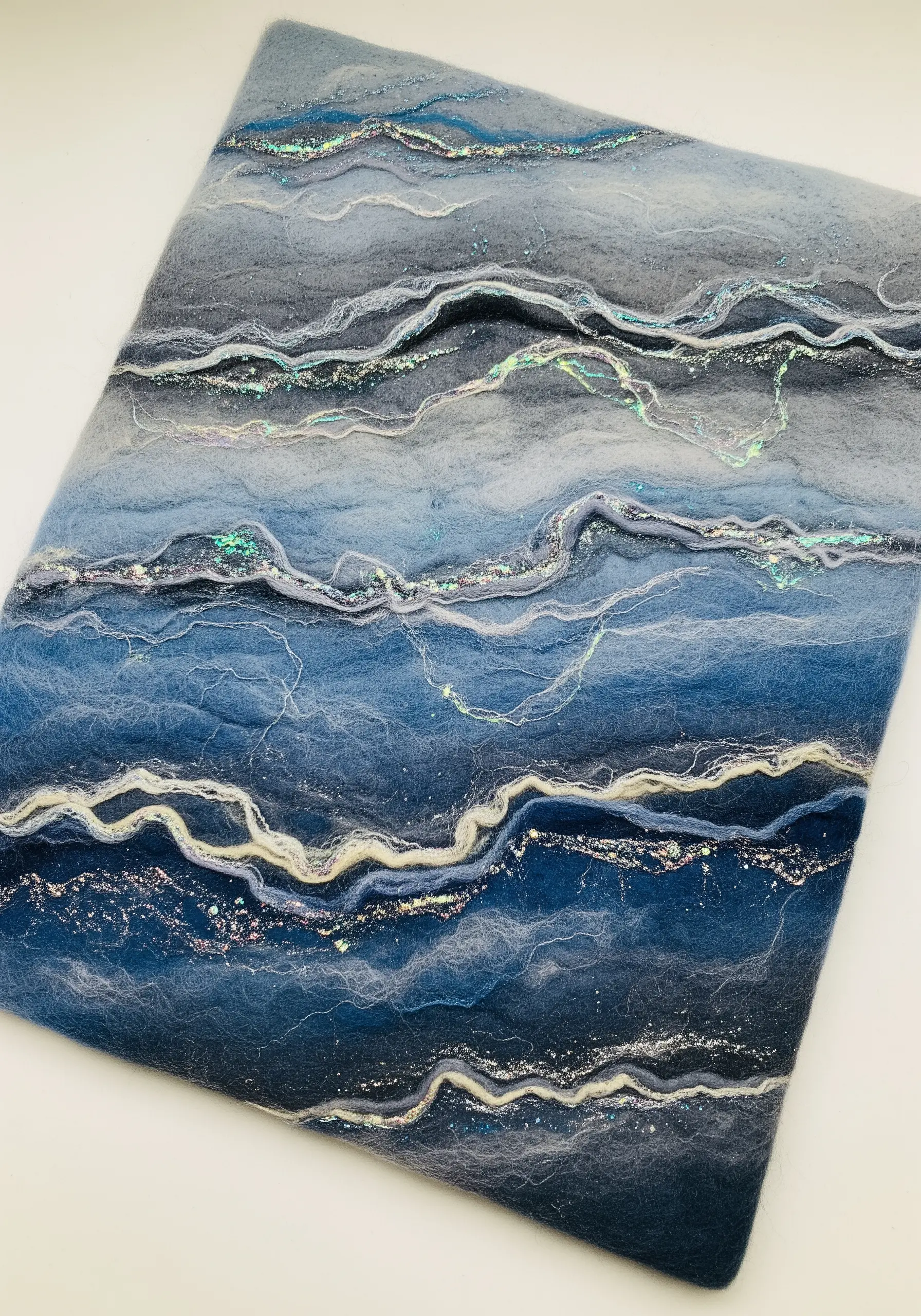 Blue and grey wet-felted wool art with shimmering iridescent Angelina fibers.