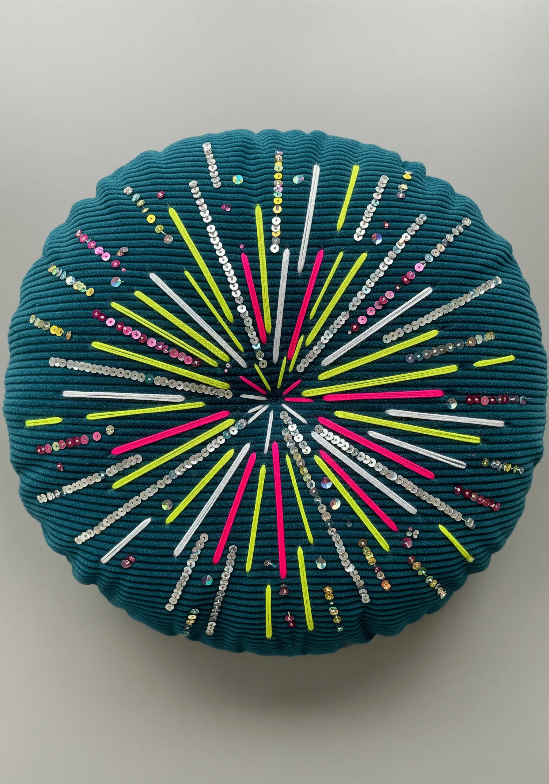 Fireworks design with neon thread, silver sequins, and bugle beads on a teal pillow.