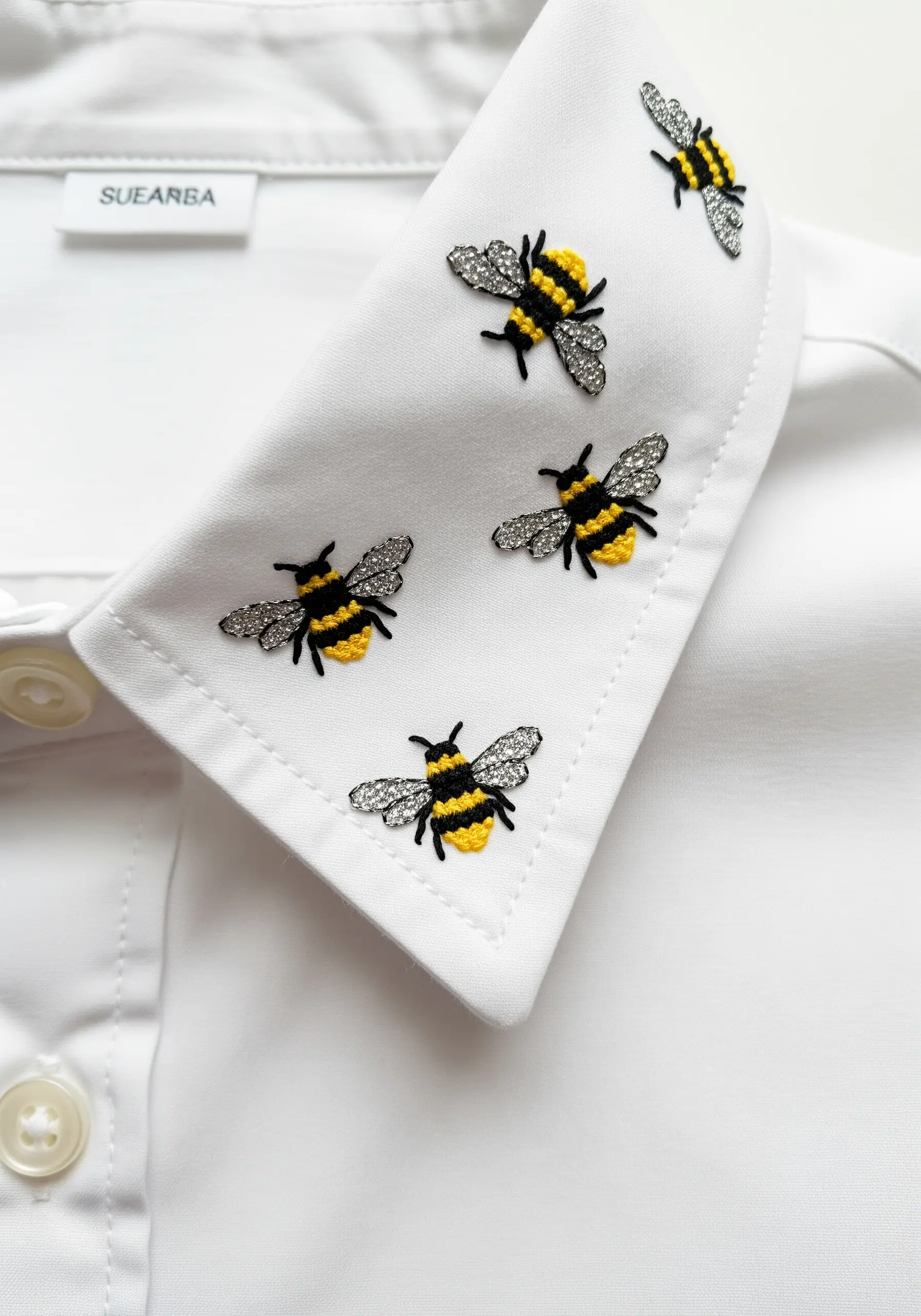 Tiny cross-stitched bees with beaded wings scattered on the collar of a white dress shirt.