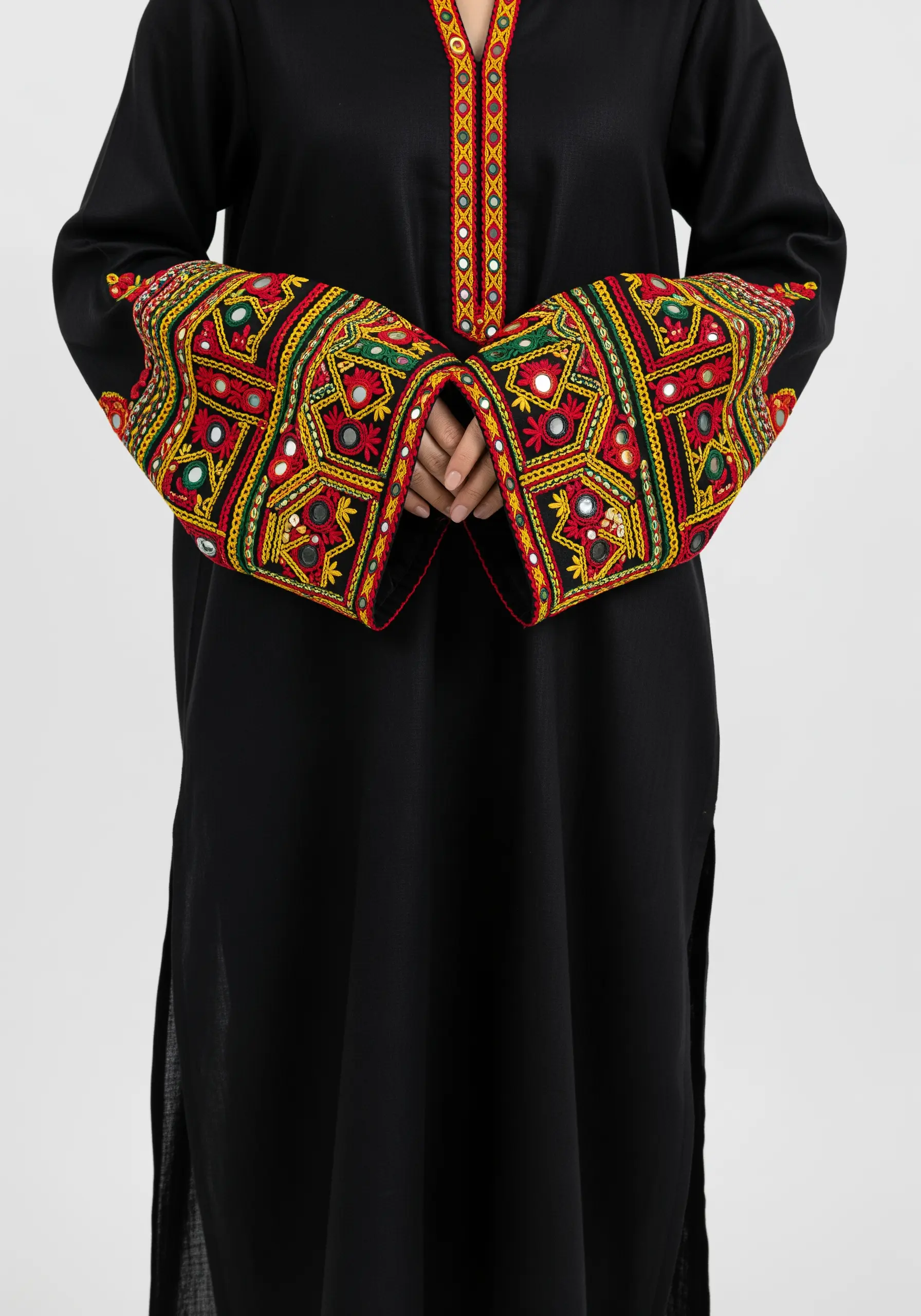 Elaborately embroidered cuffs on a black tunic, featuring colorful geometric patterns and shisha mirrors.