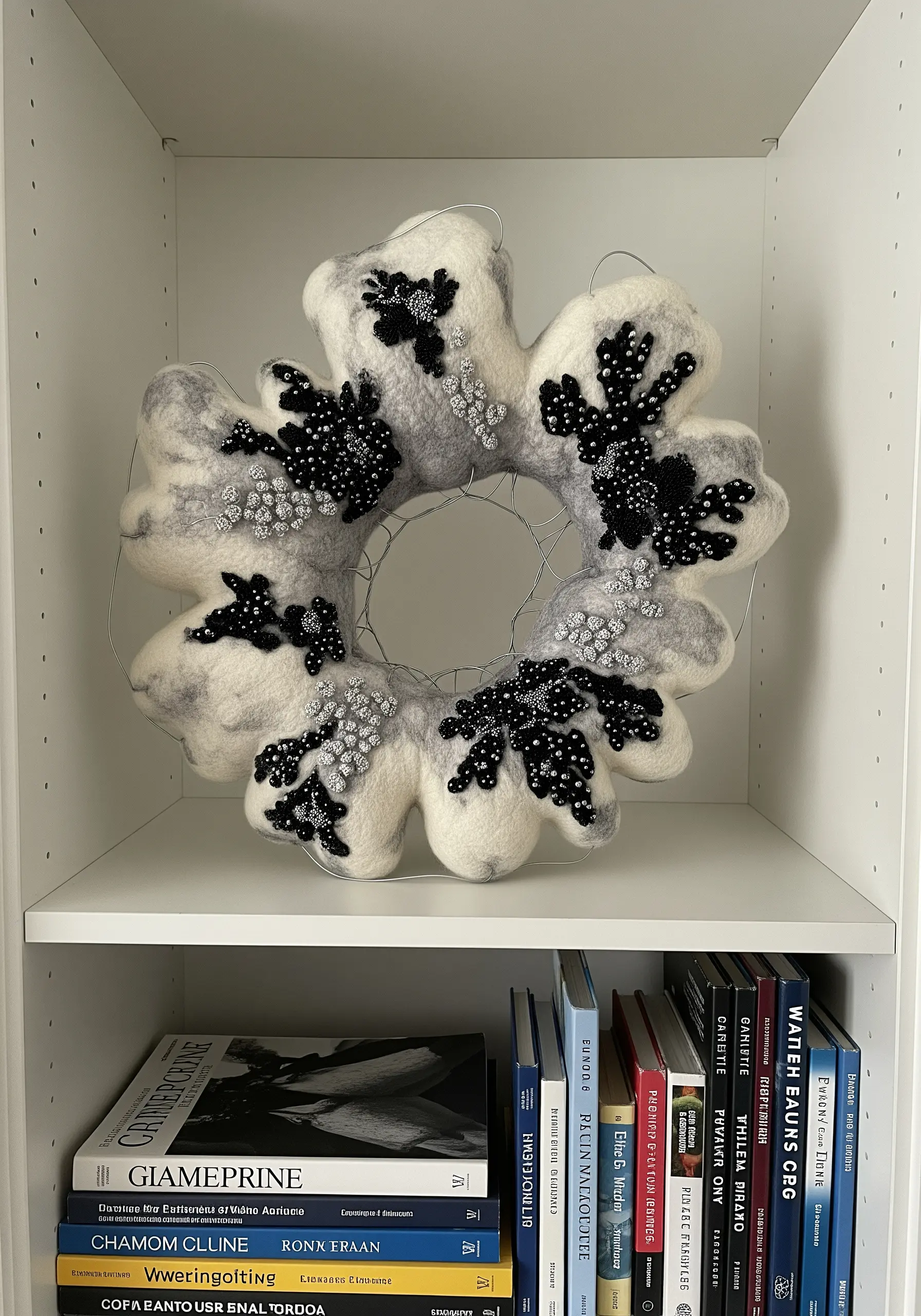 A gray felted wool wreath embellished with clusters of black and silver beads.