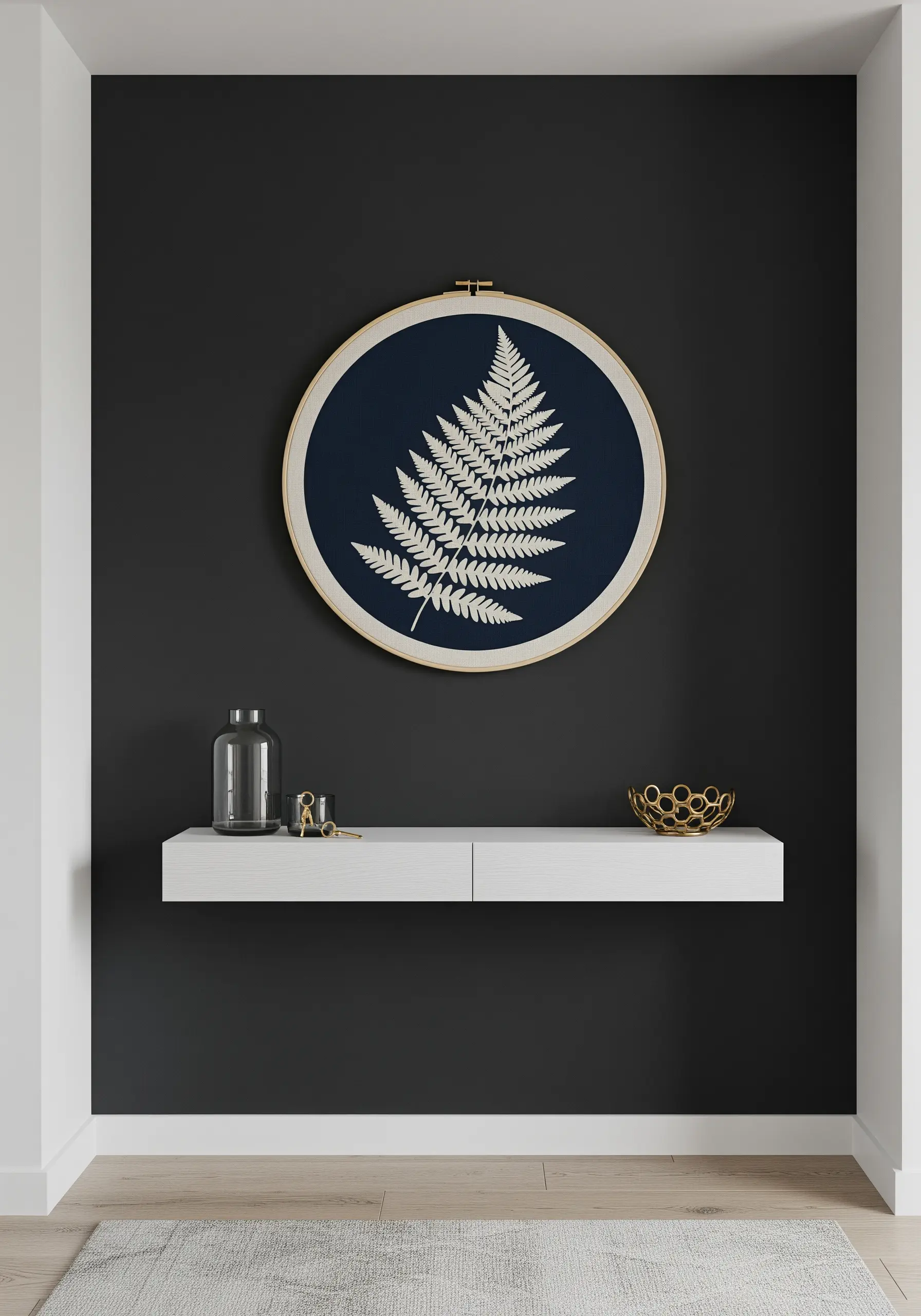 A single white embroidered fern on dark navy fabric in a gold-toned hoop.